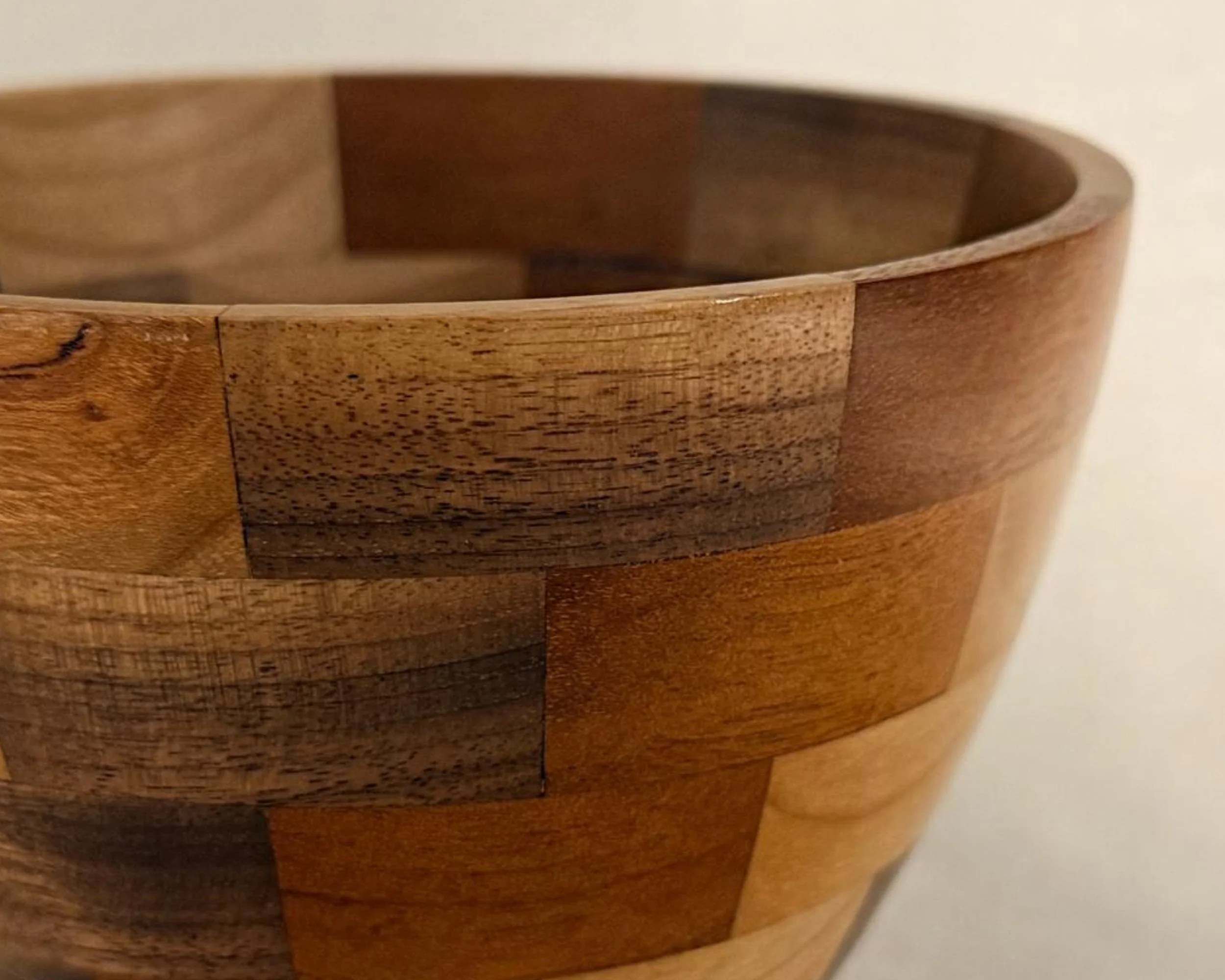 Rim detail of segmented walnut, padauk, and maple vessel showing clean joints and block transitions.
