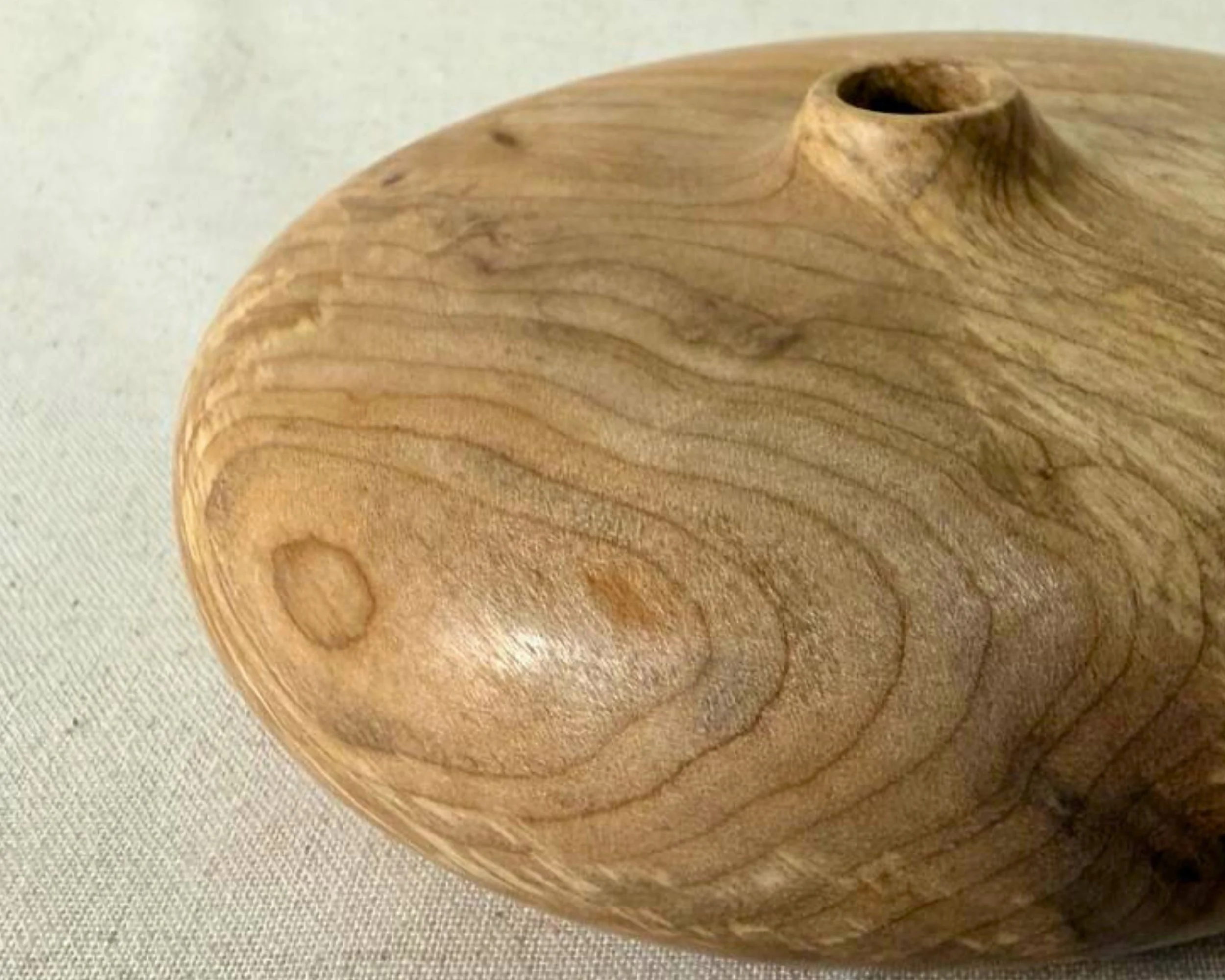 Close-up of the opening area on the figured maple vessel, showing smooth turned edges and grain detail.