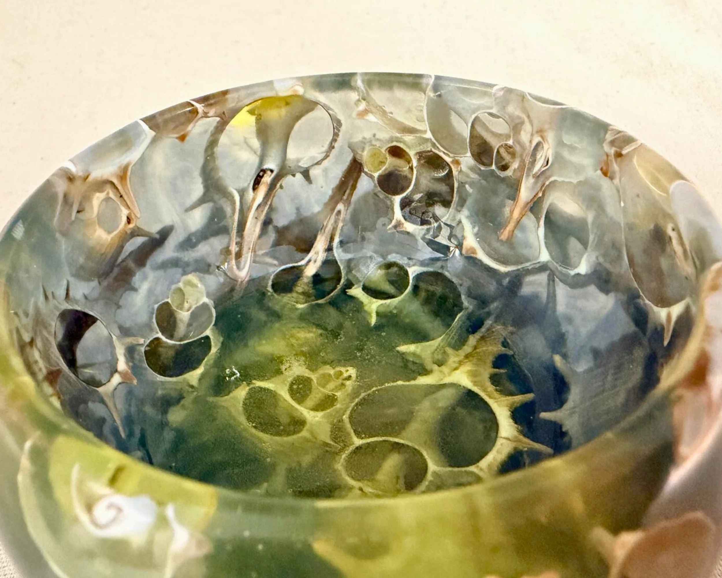 Top interior view of seashell and epoxy vessel showing layered shell fragments in translucent green-blue resin.