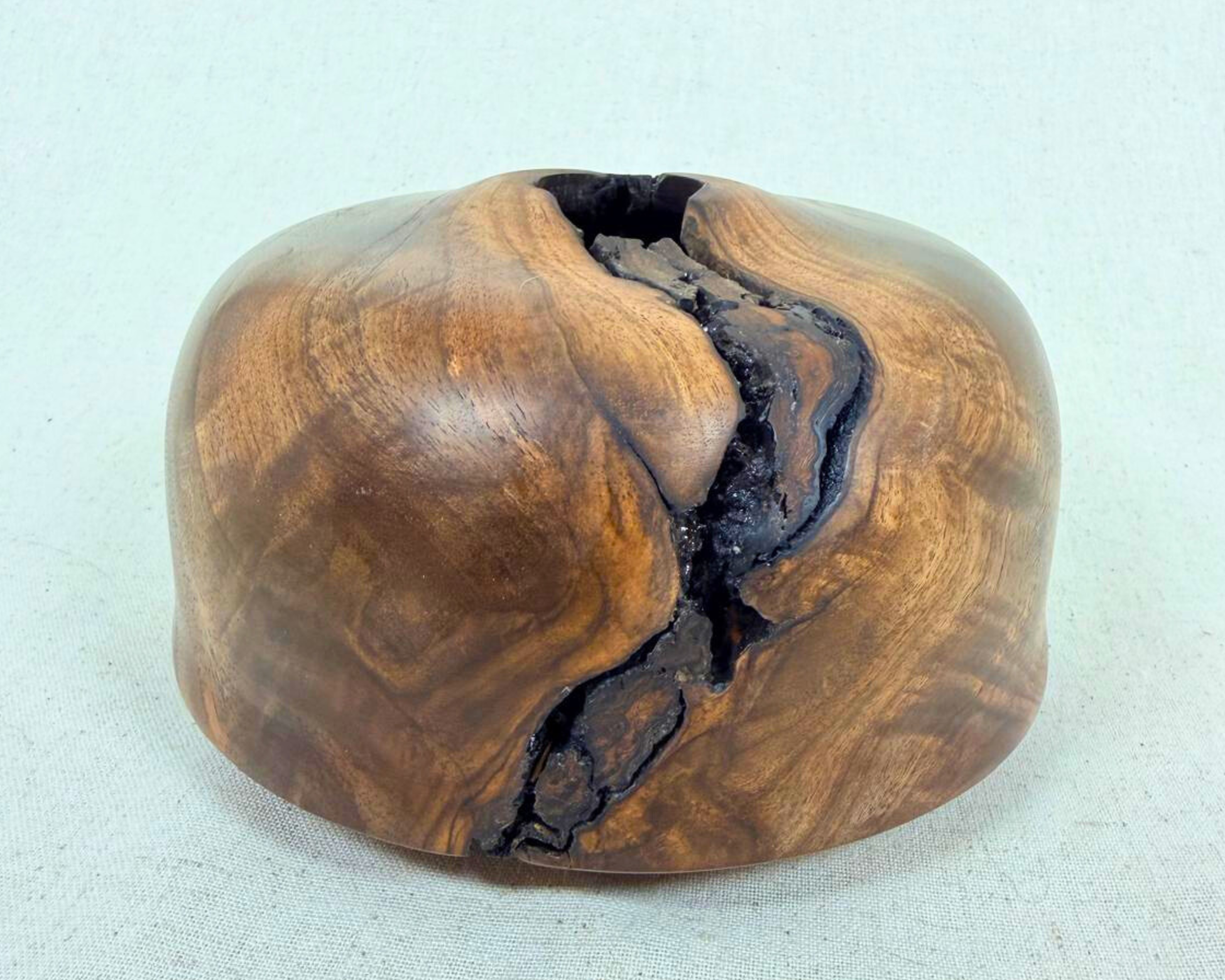 Front-facing walnut vessel with soft rounded volume and a deep natural void opening that travels vertically through the form.