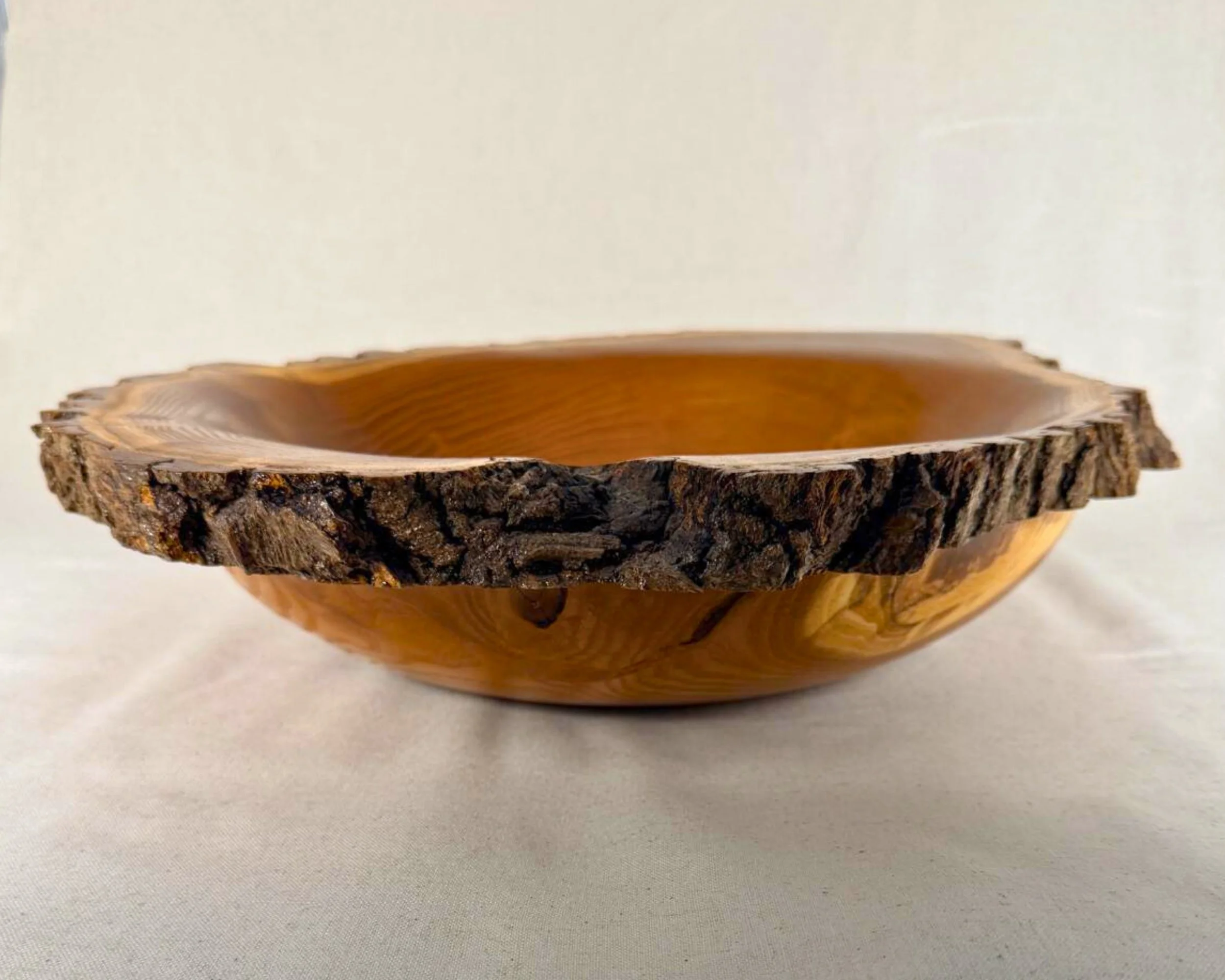 Side profile of mulberry live-edge bowl with rugged bark rim and shallow form