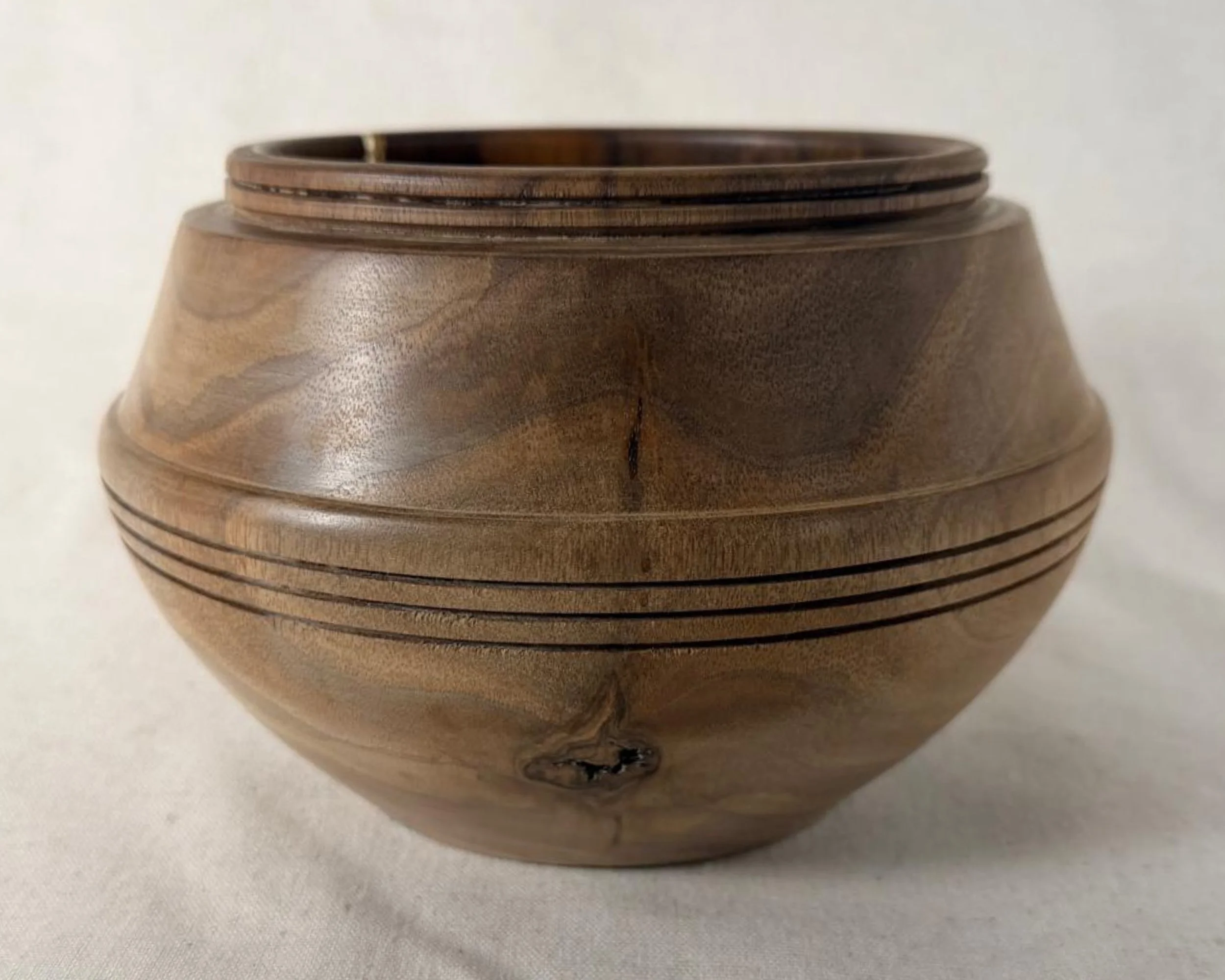 Walnut bowl with neutral-toned epoxy accent, rounded profile, and banded detail on a light linen background.