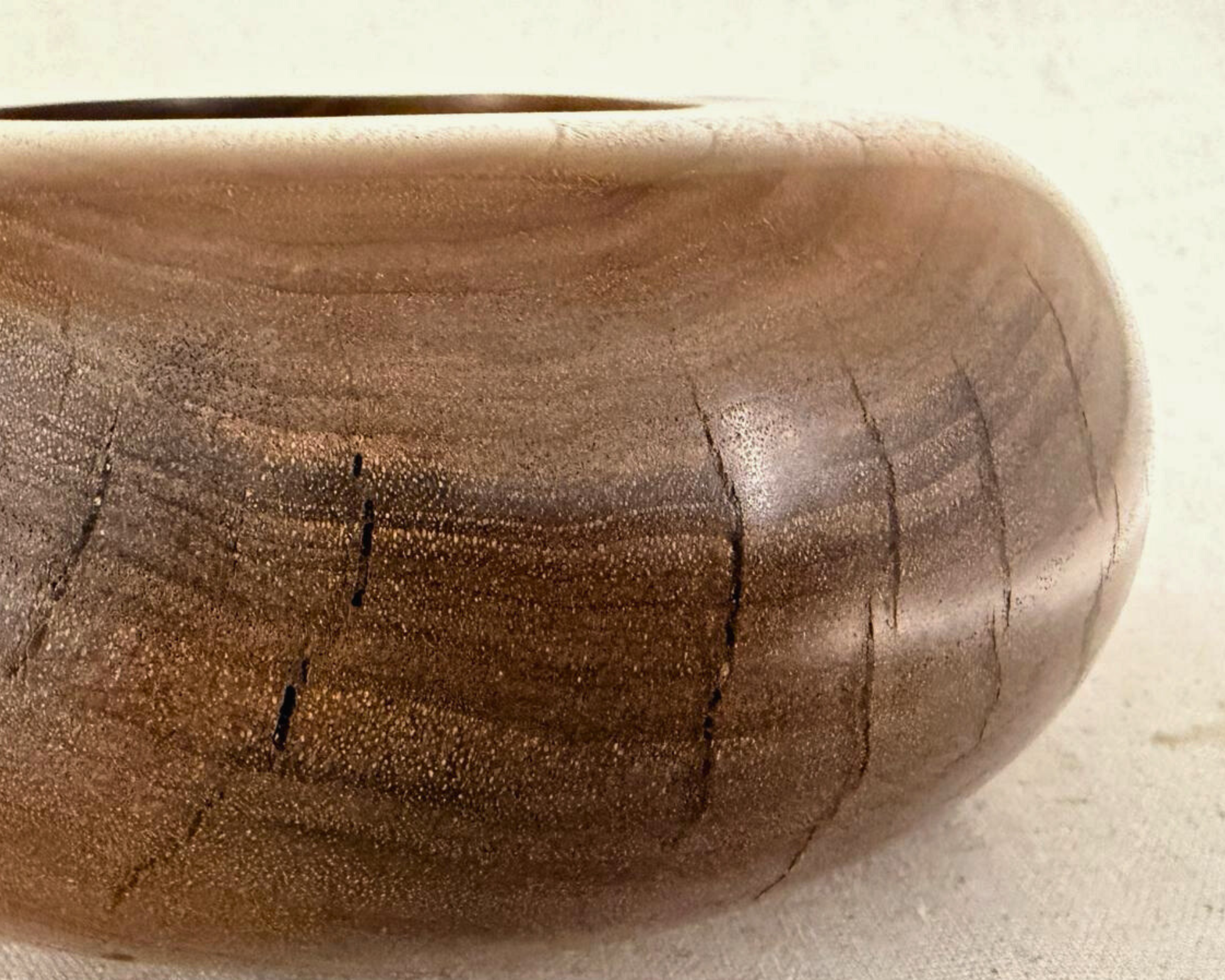 Close-up detail of claro walnut grain with natural checking lines and soft tonal shifts across the surface.