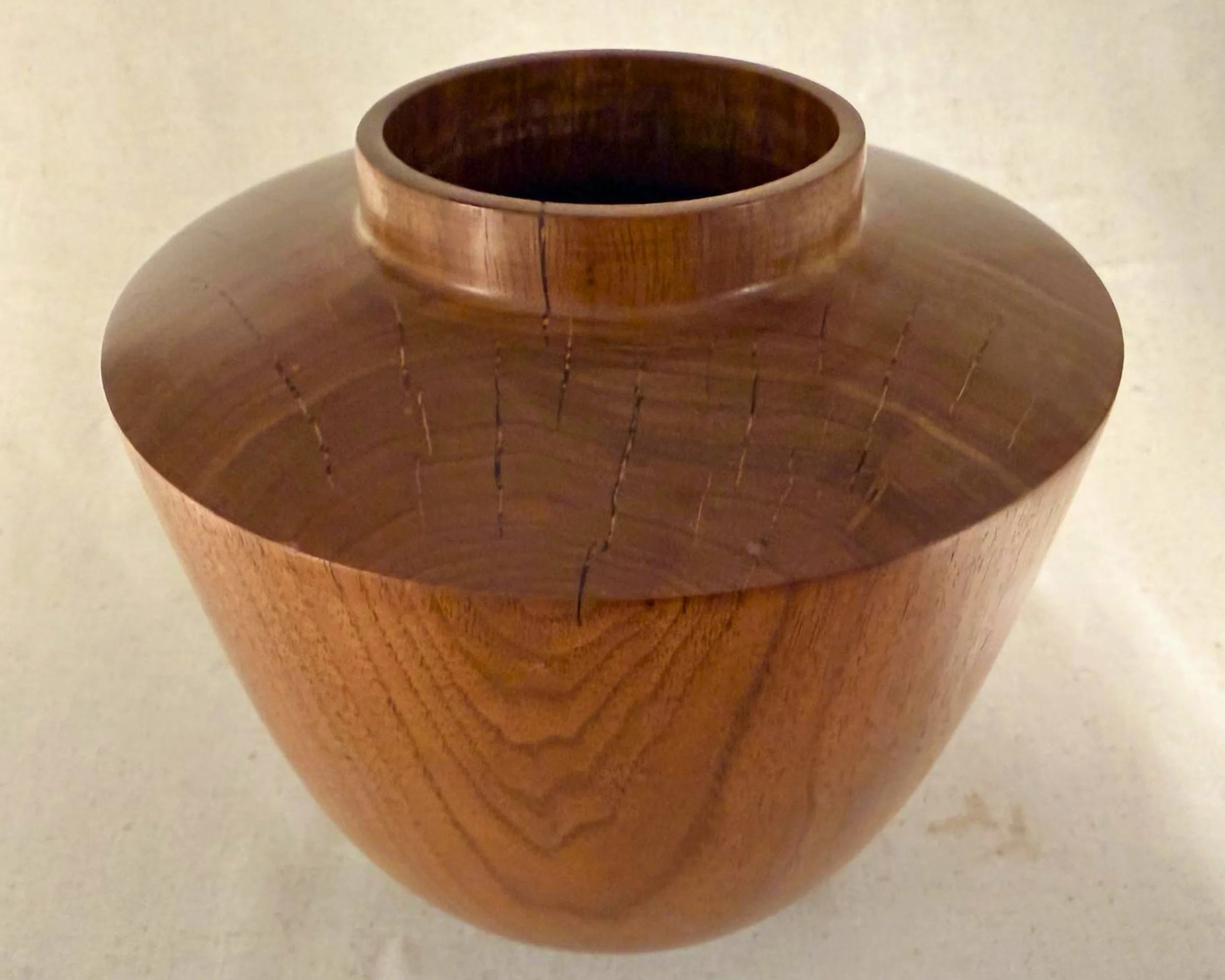 Angled top view of walnut vessel highlighting surface checking filled with black epoxy and the raised collar opening.