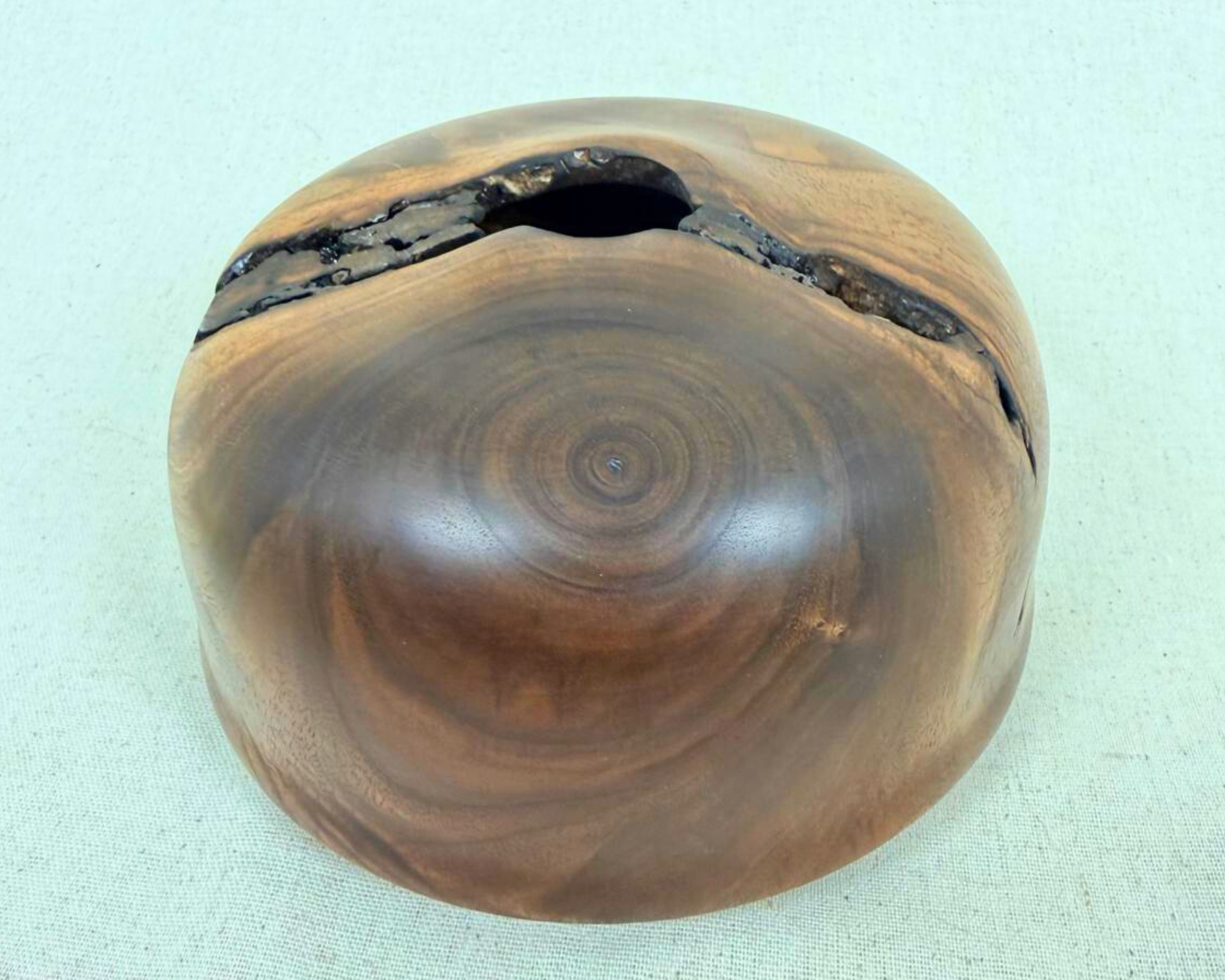 Top detail of the walnut vessel showing the 1-inch opening, rugged natural void structure, and dark bark-like interior that passes fully through the piece.