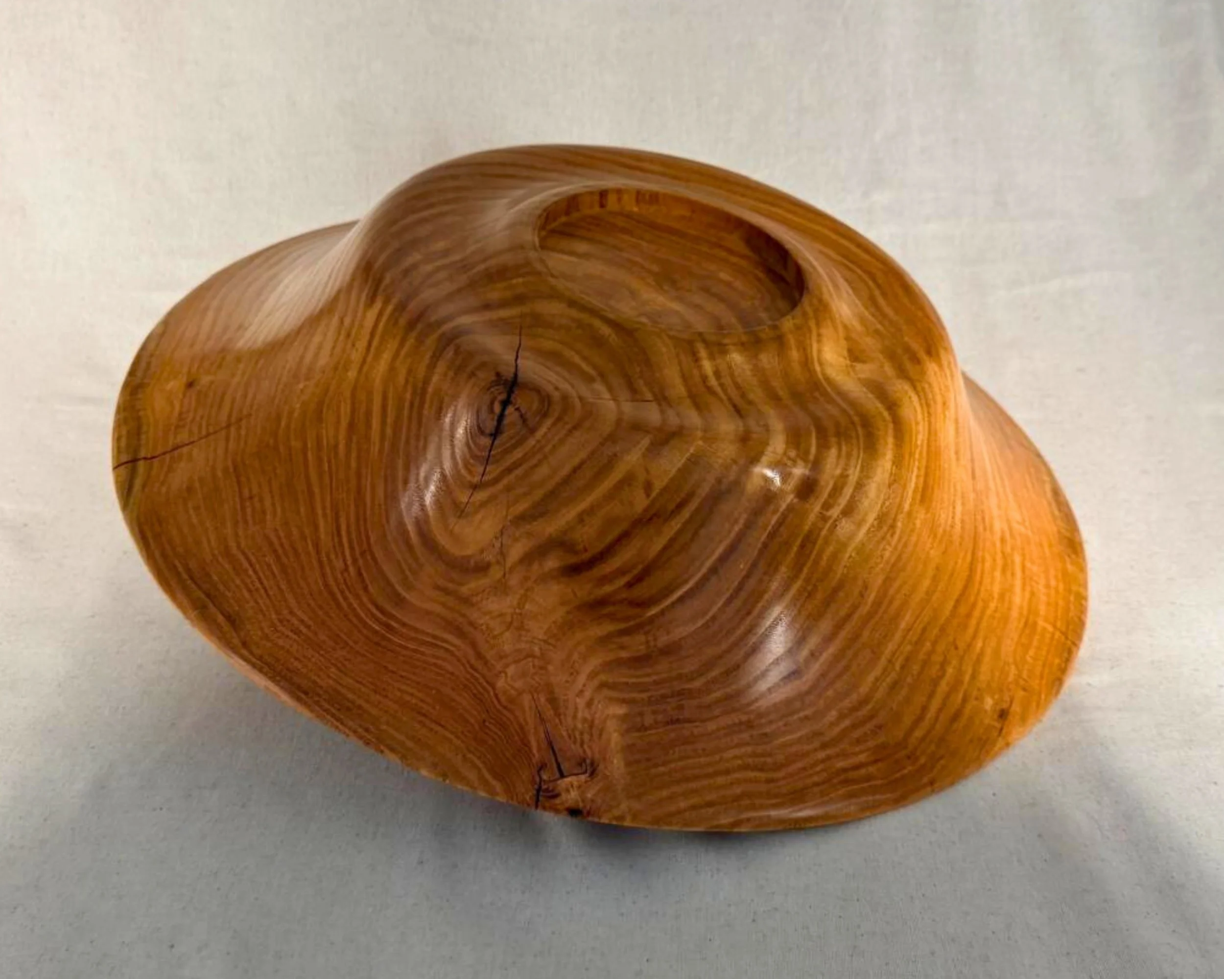 Underside view of the honey locust platter showing turned foot ring and natural checking with epoxy accents