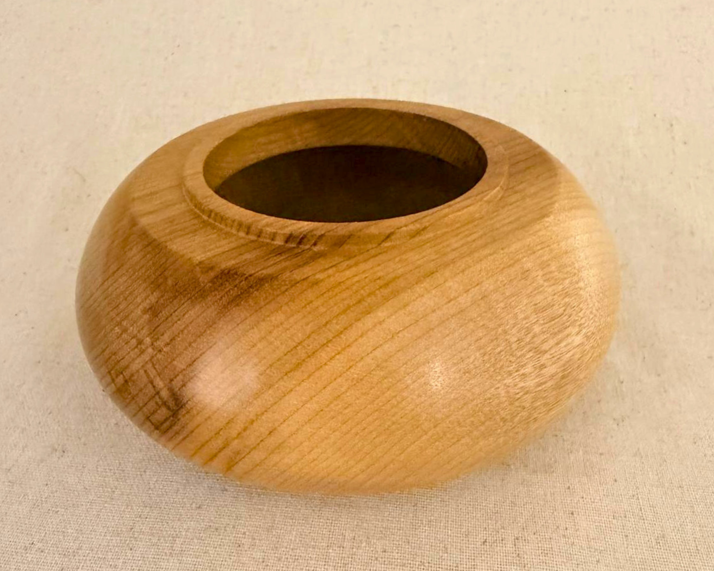 Overhead view of a hand-turned myrtle vessel showing circular opening, raised rim, and concentric grain across the rounded form.