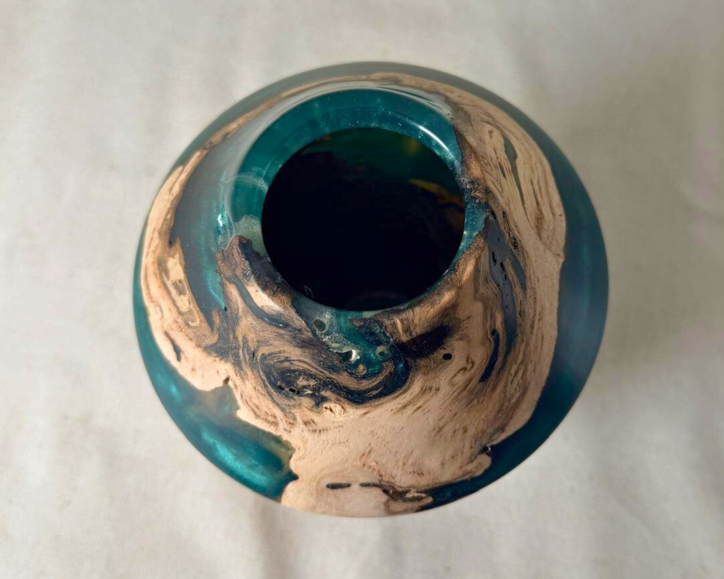 Top view of driftwood and green epoxy vessel showing the circular opening, pale driftwood figure, and deep green resin surrounding the rim.