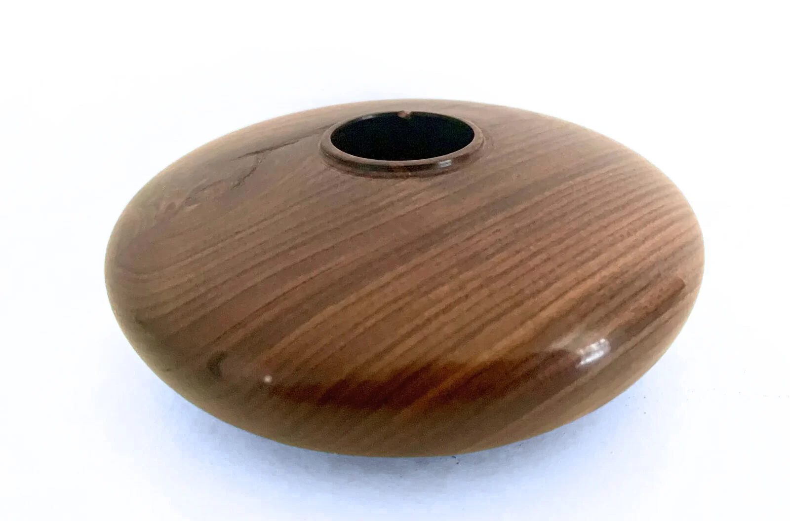A round hand-turned cherry wood vase with a small opening at the top, with visible dramatic grain patterns.