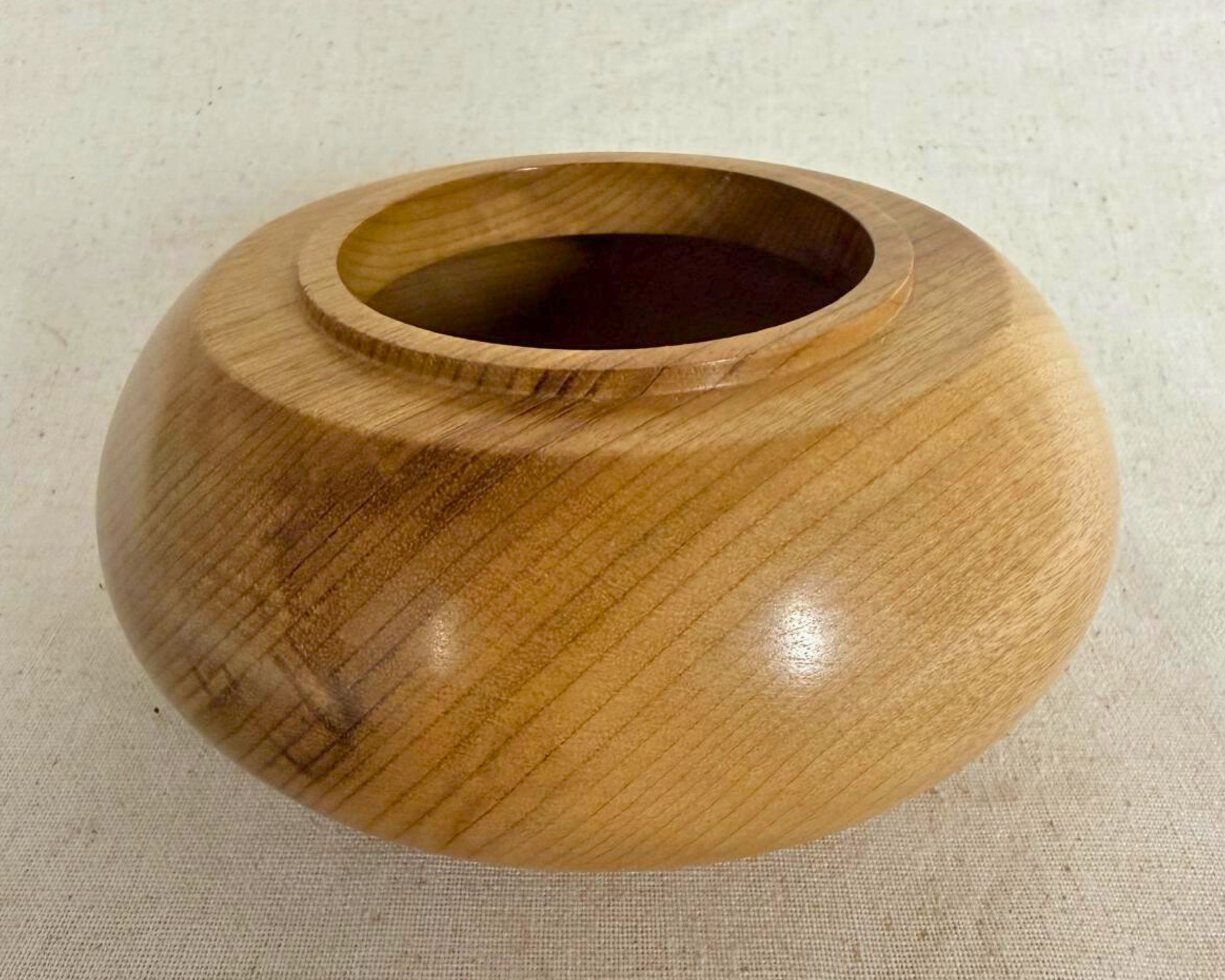 Side angle of a rounded myrtle vessel with soft honey tones, visible grain lines, and a calm sculptural profile.