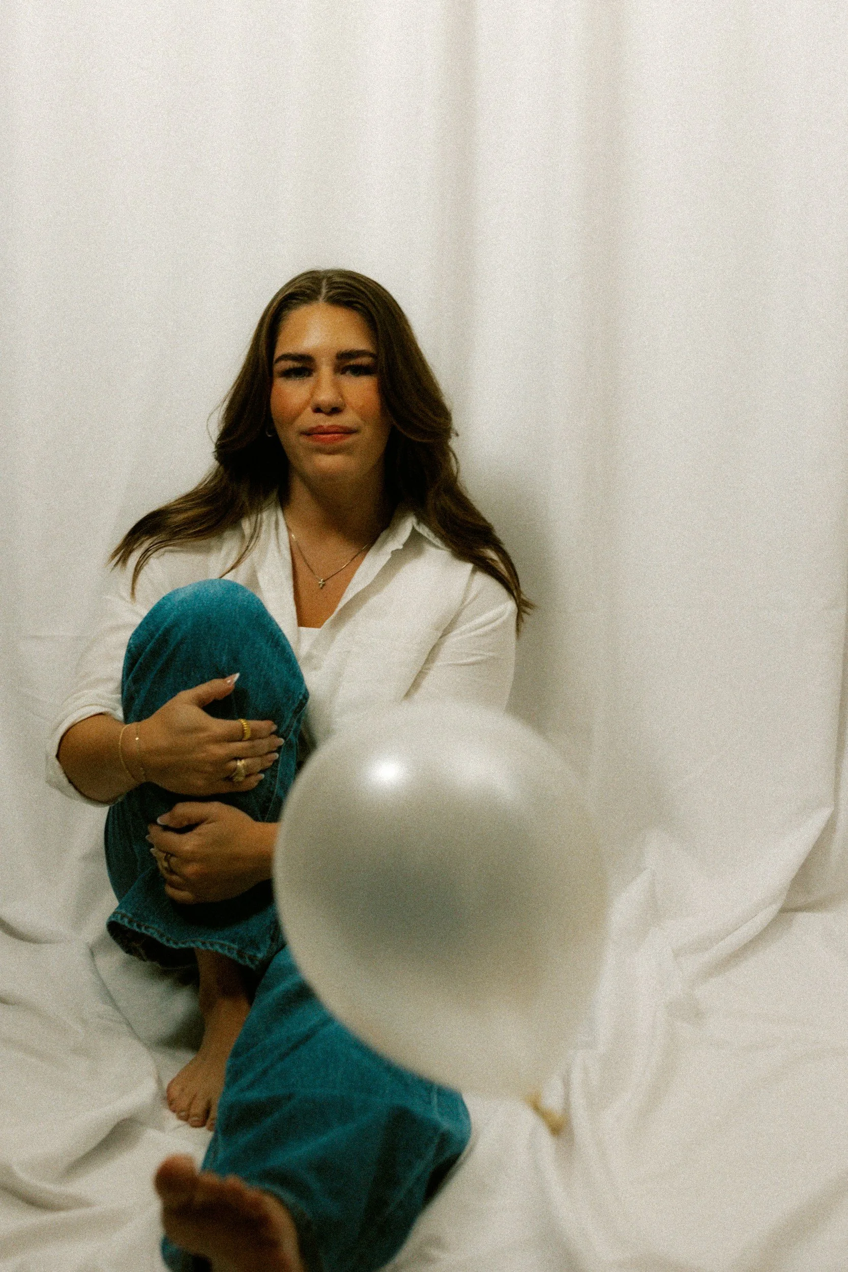 woman seating looking at a white balloon