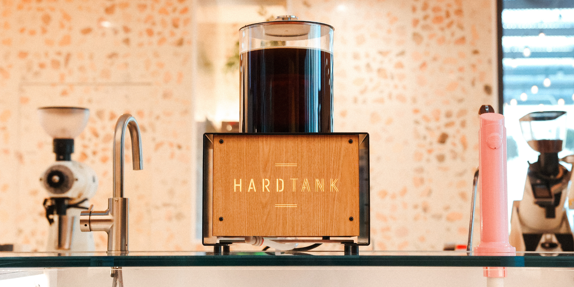 Coffee being brewed in a FETCO HARDTANK cold brewer in a cafe with a textured brick wall in the background.