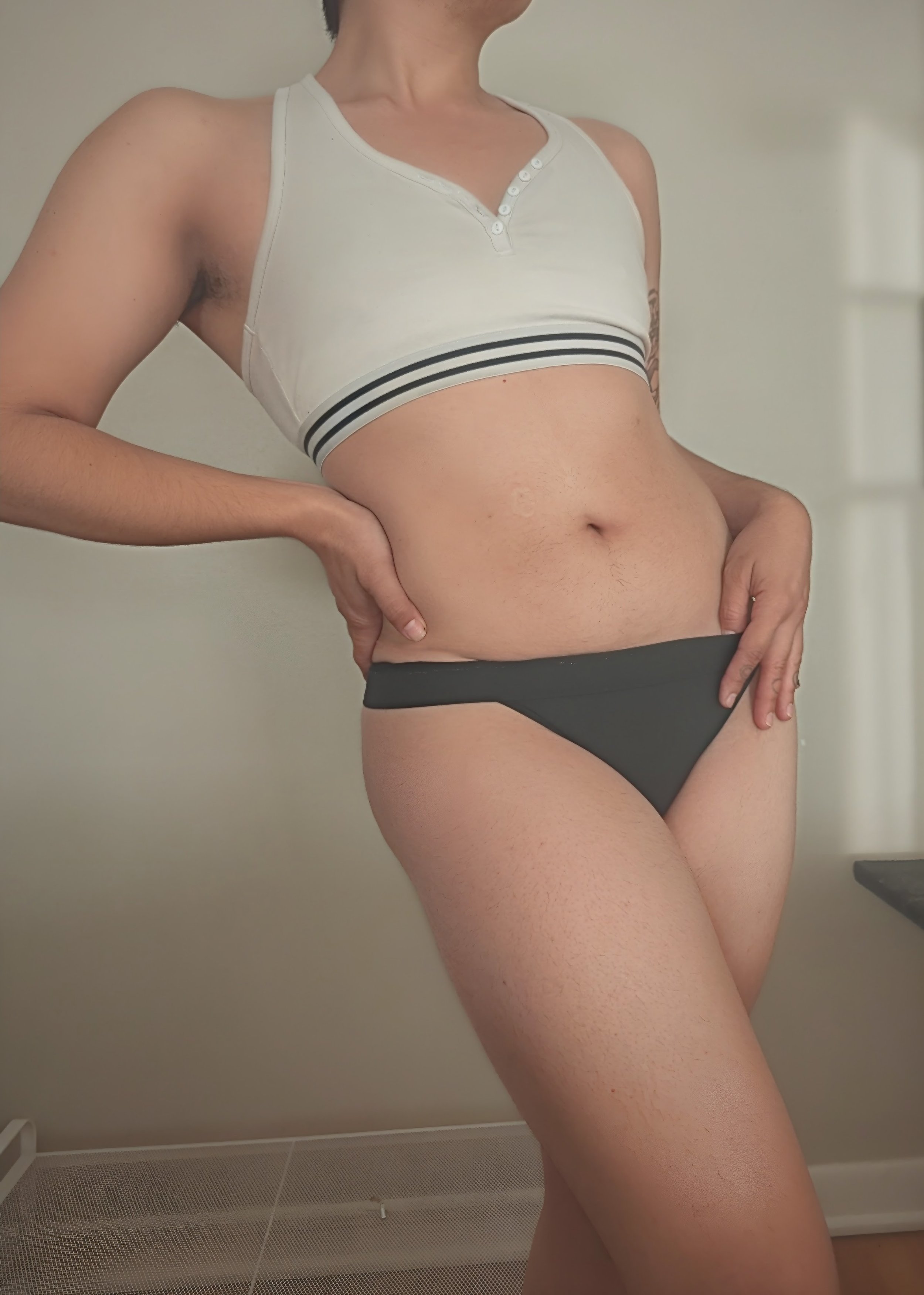 An image of Thorne Vo standing in a relaxed position wearing a white sports bra and black panties.