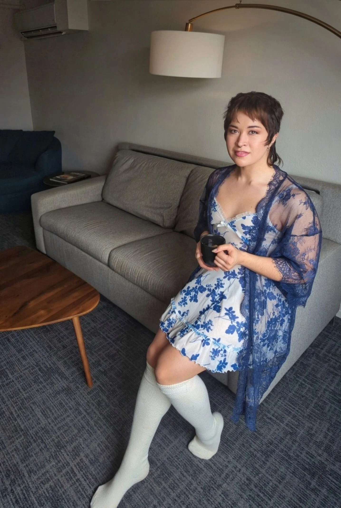 An image of Thorne Vo perched on the armrest of a couch while holding a warm mug of tea.