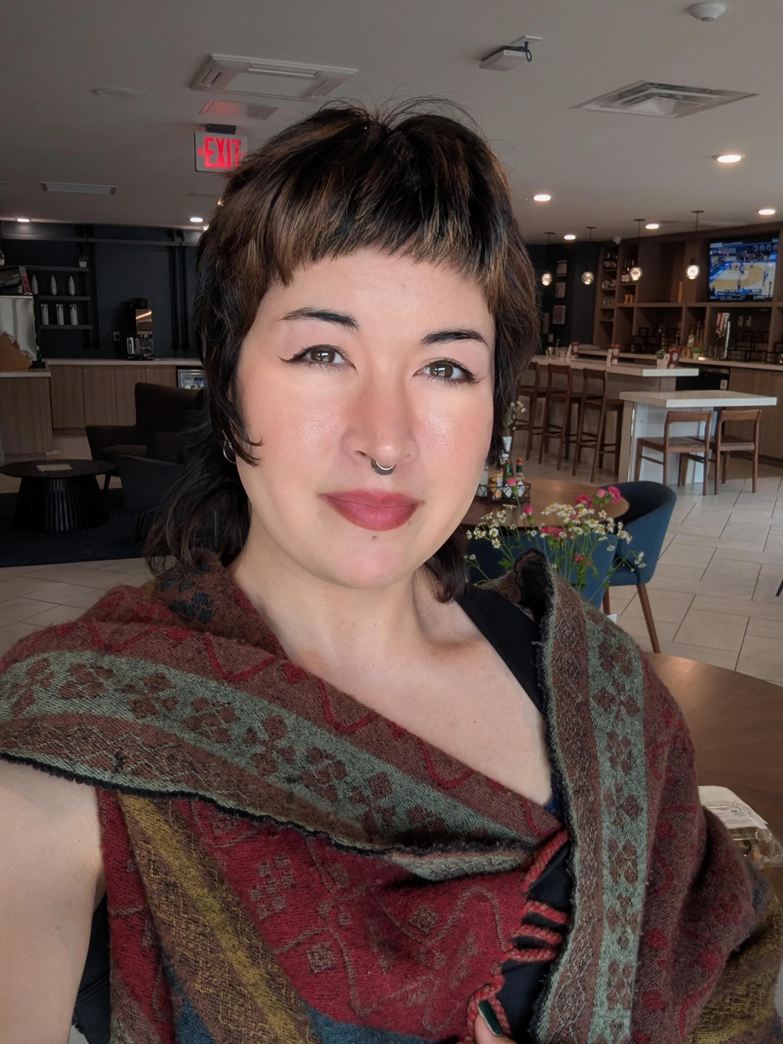 Thorne Vo smiling in a restaurant while wearing am ornate wool scarf.