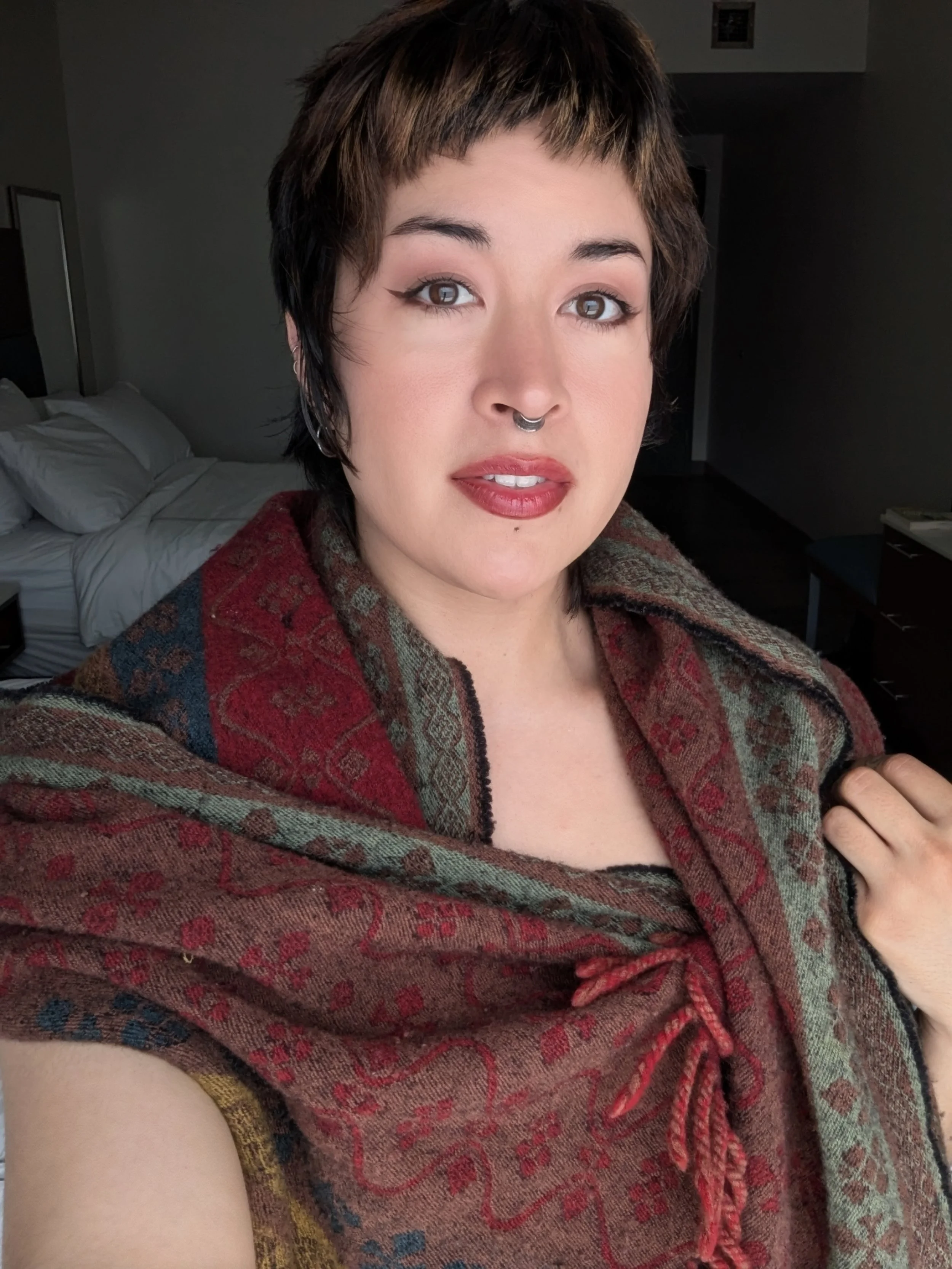 A close-up photo of Thorn Vo wearing a woolen scarf in a clean bedroom.