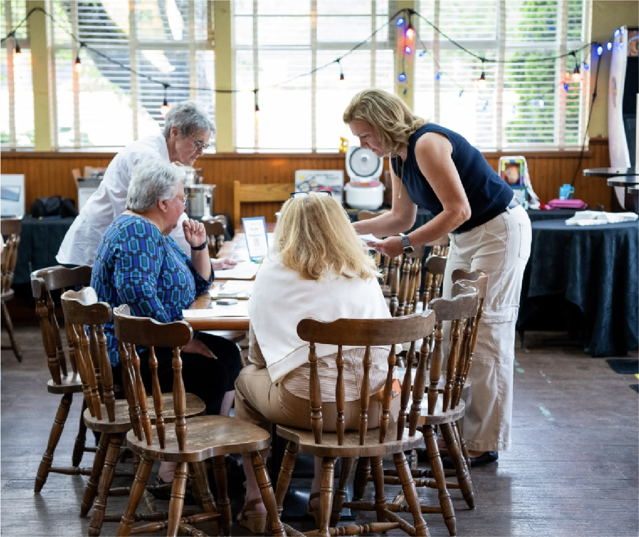 Voters at a table registering for an election at a restaurant or cafe with string lights.