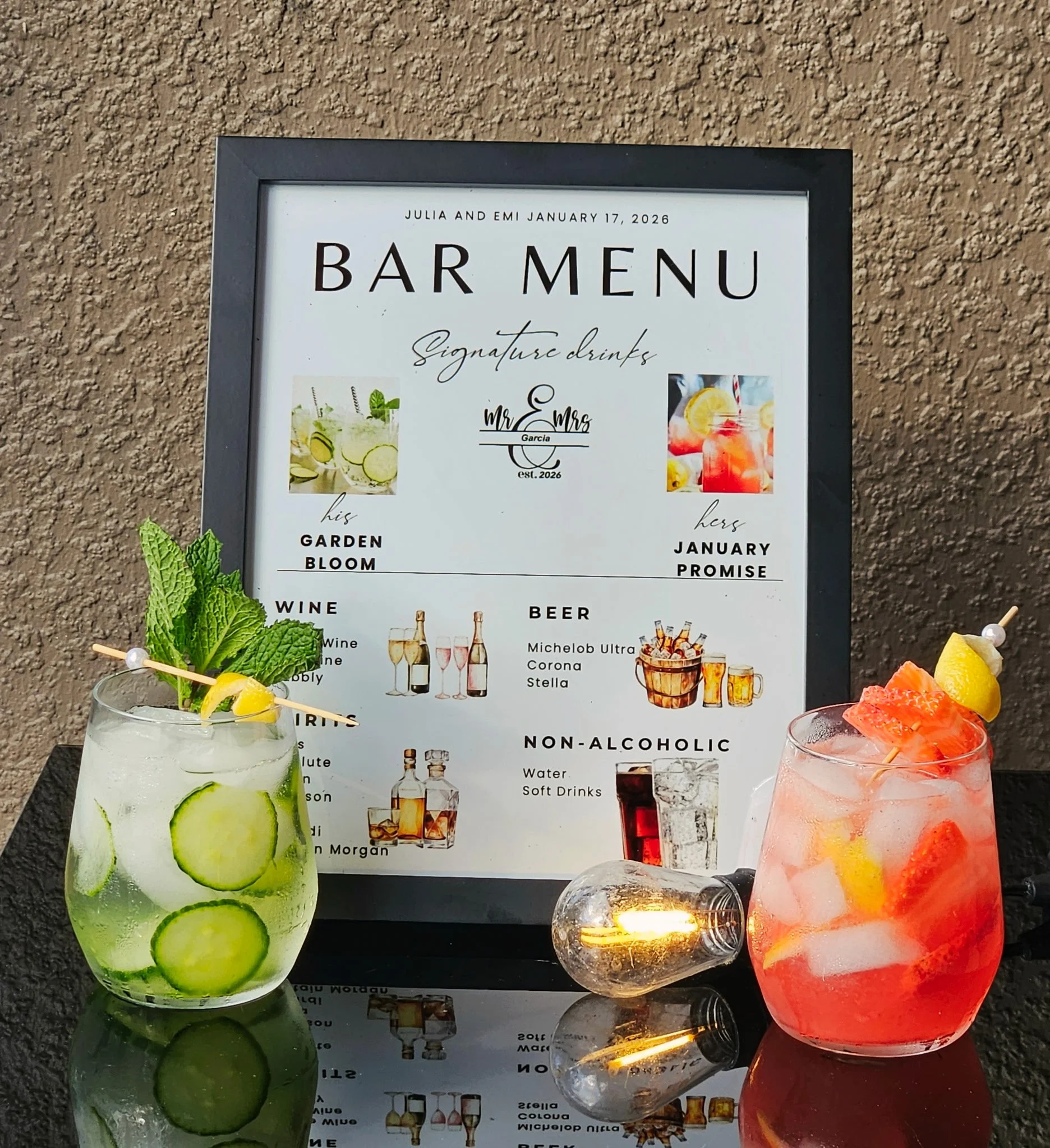 Two colorful cocktails on a table in front of a bar menu sign. The drink on the left is a clear, chilled beverage with sliced cucumbers and fresh mint leaves, garnished with lemon and cucumber slices on a skewer. The drink on the right is a pinkish cocktail with ice, topped with citrus slices and a small piece of fruit. The bar menu features signature drinks, wines, beers, and non-alcoholic options, with the bar's name and date at the top.