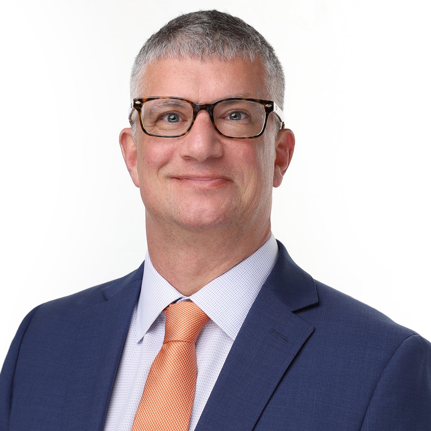 Professional headshot of a man wearing glasses, a navy suit, a white shirt, and an orange tie, against a white background.