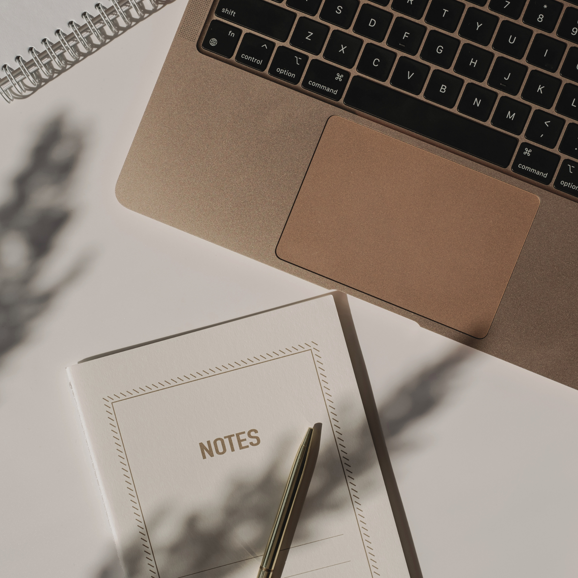 Notepad, pen and gold laptop