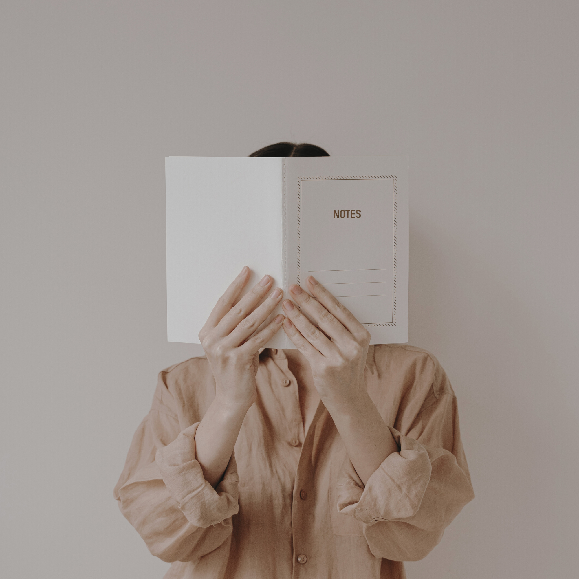 Woman with face hidden by notebook