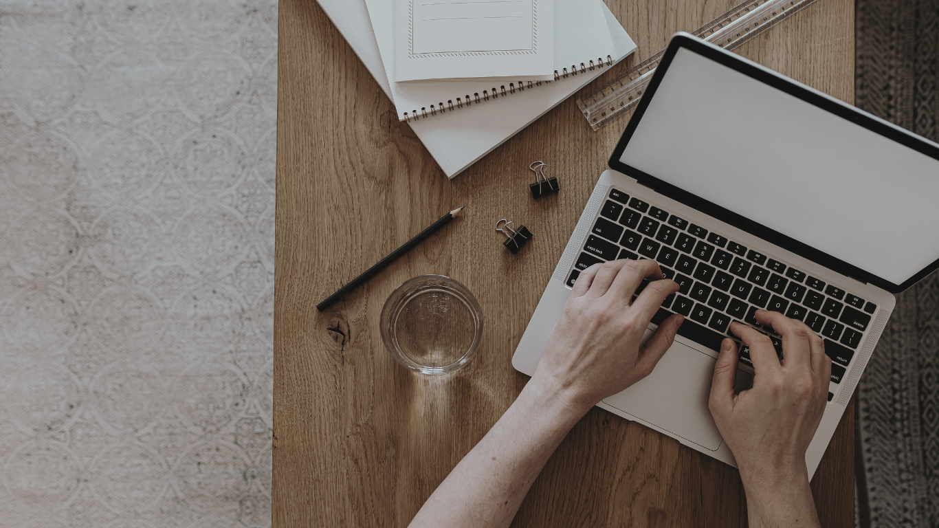 Woman's hands on laptop on wooden desk