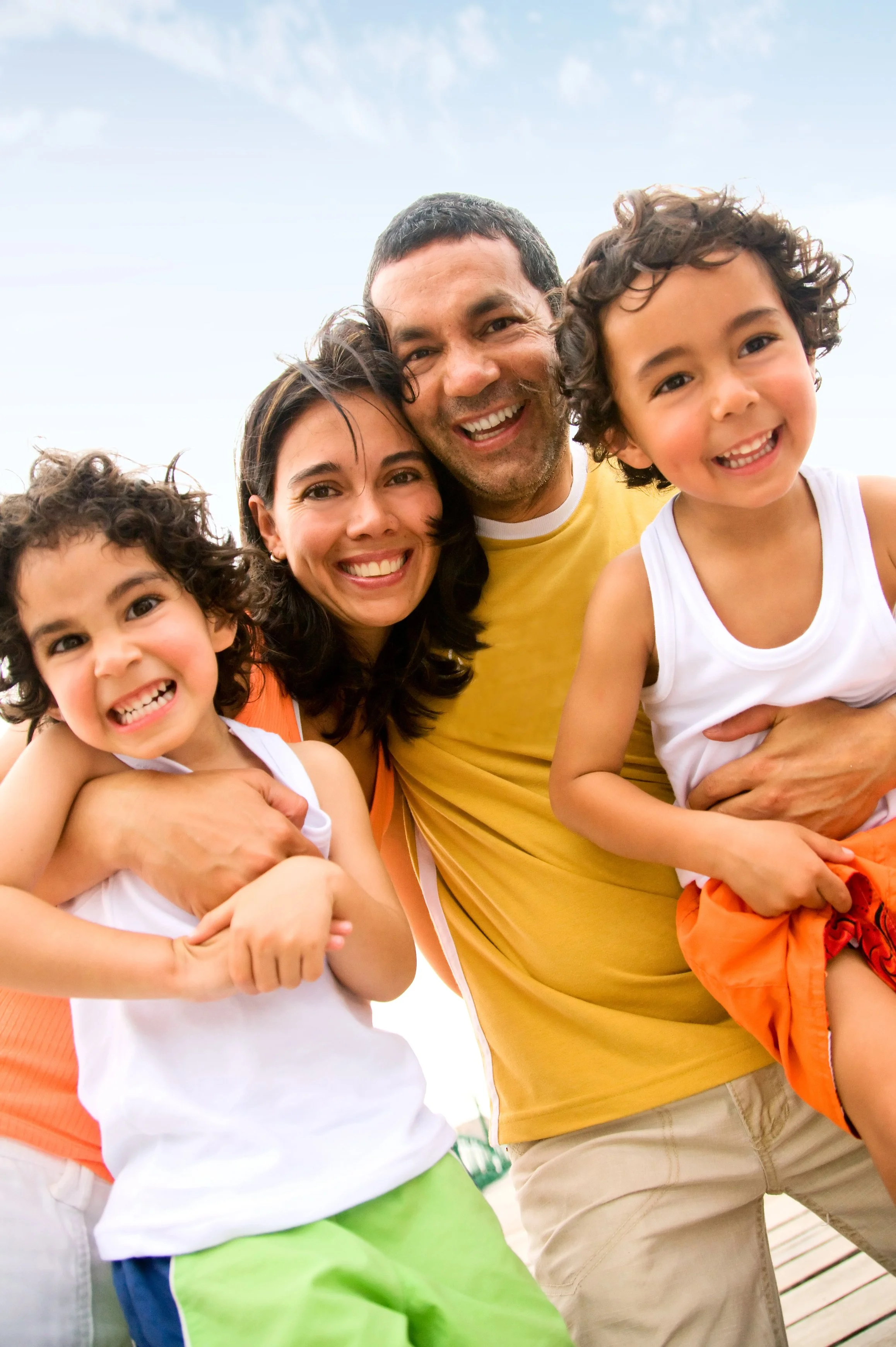 Familia sonriendo en el parque, con niños pequeños y adultos felices.