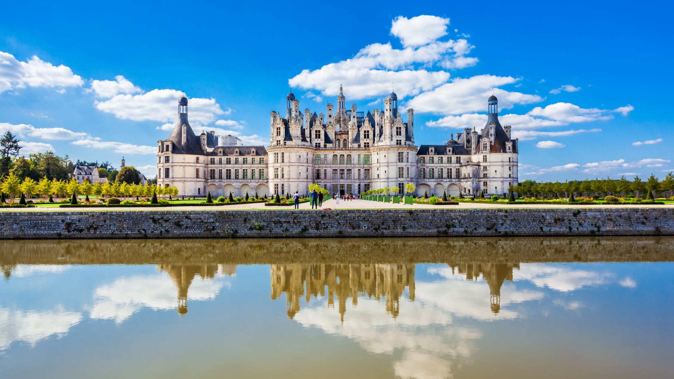 Photo of entrance of Chambord Castle in France with blue skies and white clouds