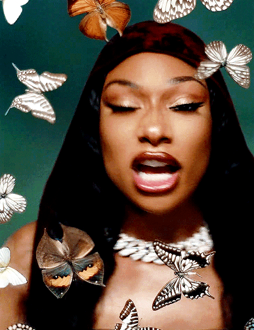 Close-up of a woman with long black hair surrounded by various butterflies.