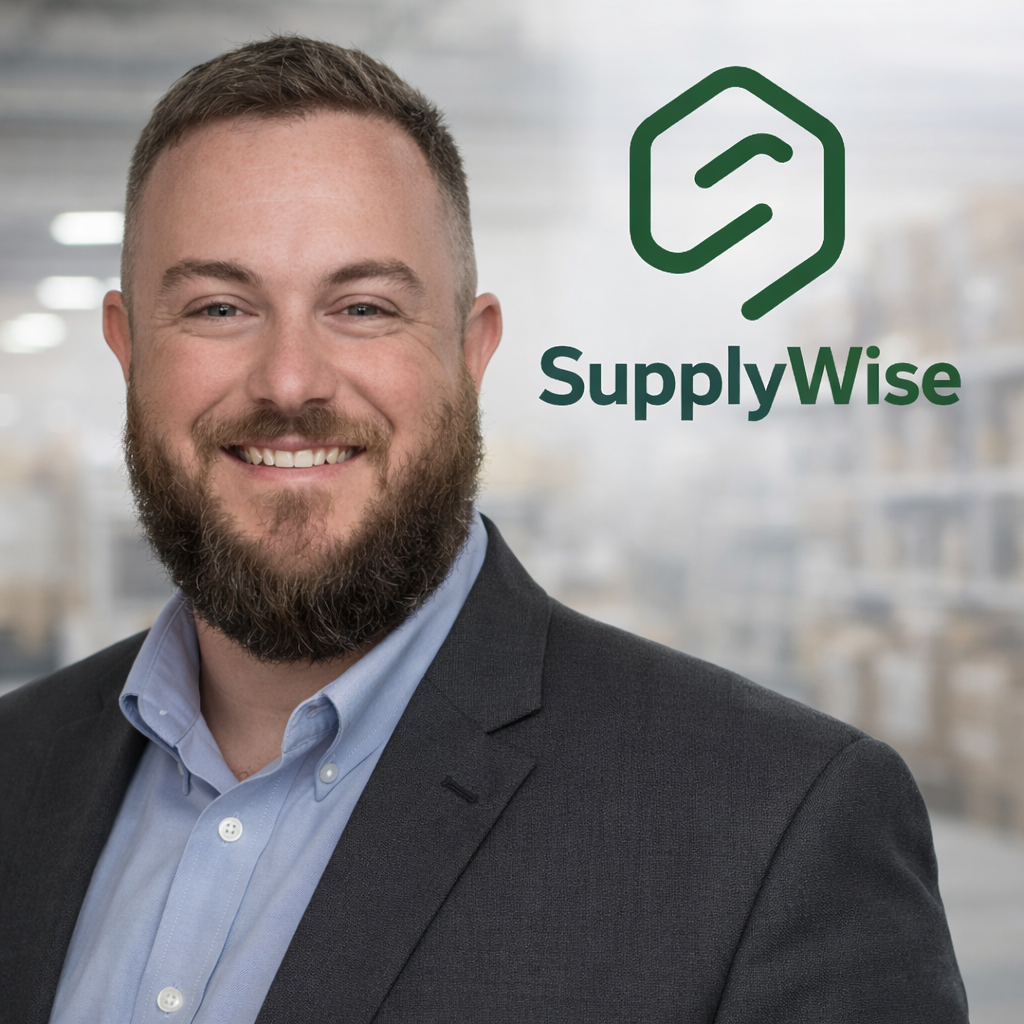 A smiling man in a suit, standing in a warehouse with shelves in the background, with a SupplyWise logo next to him.