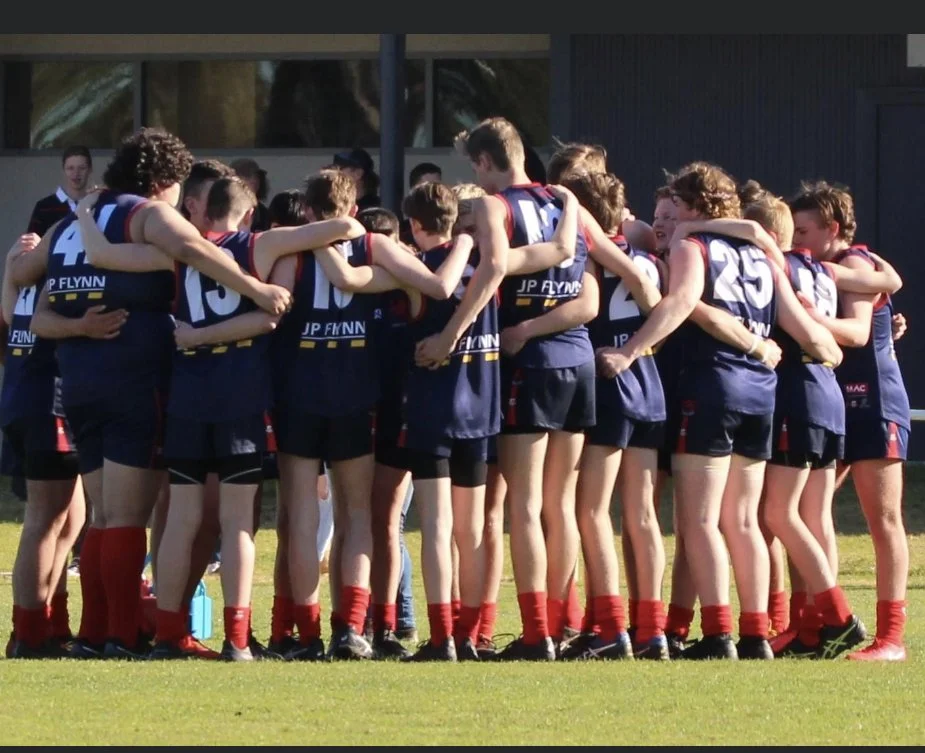 Youth sports team huddled together on a field after a game.