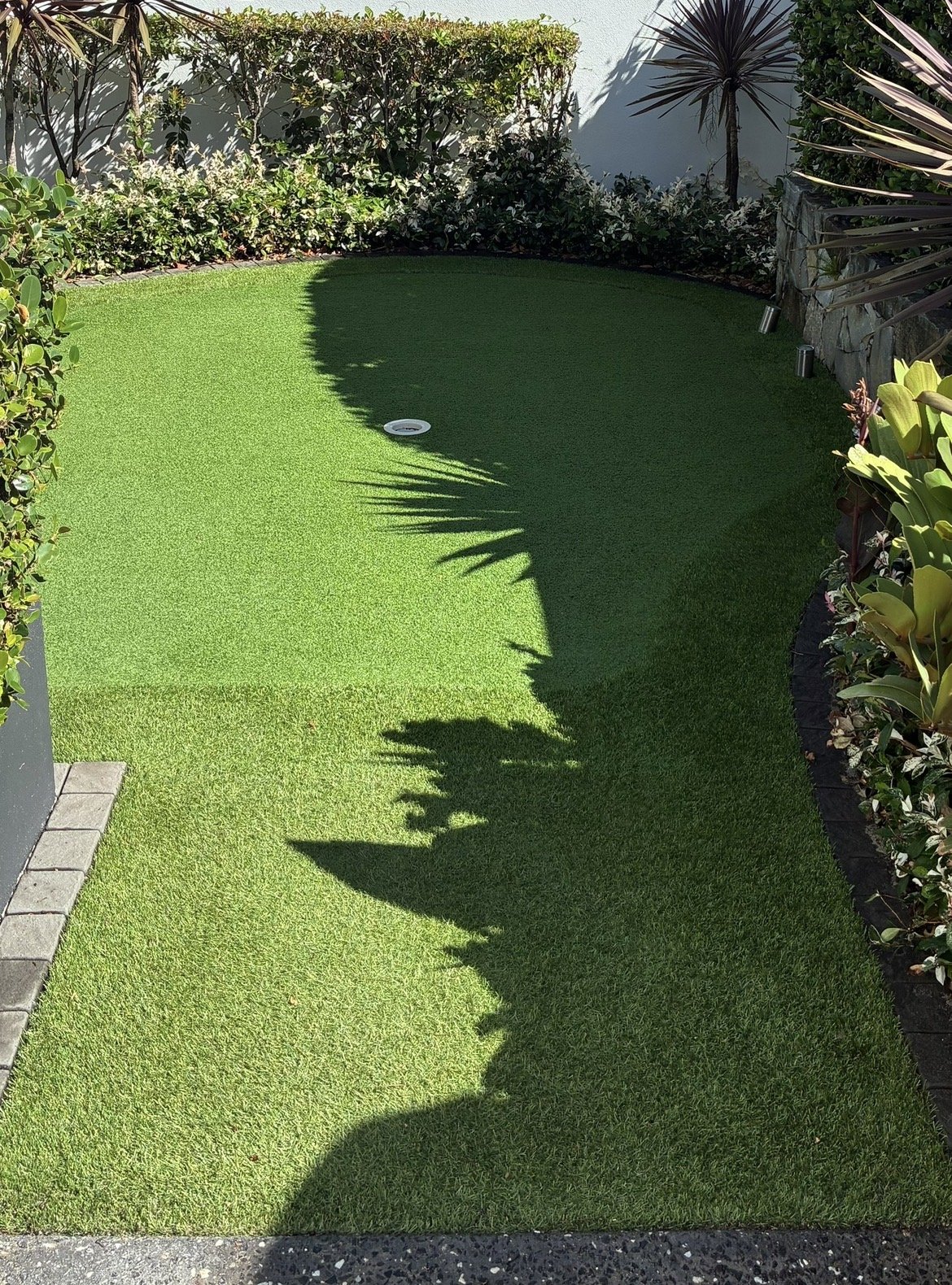 Backyard synthetic putting green with cup and garden border, Sunshine Coast