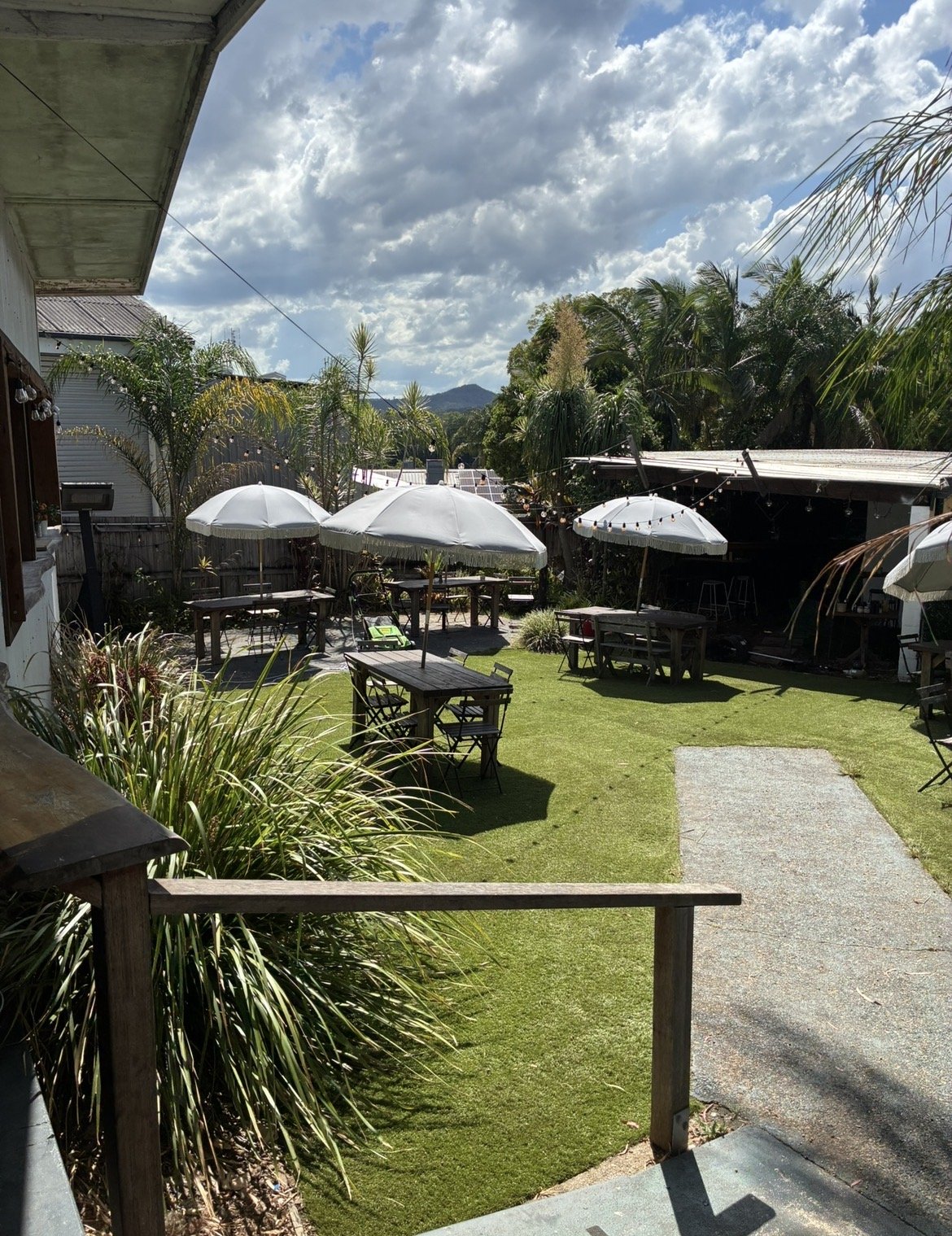 Synthetic turf courtyard at a Sunshine Coast Hospitality cafe venue with outdoor seating and umbrellas