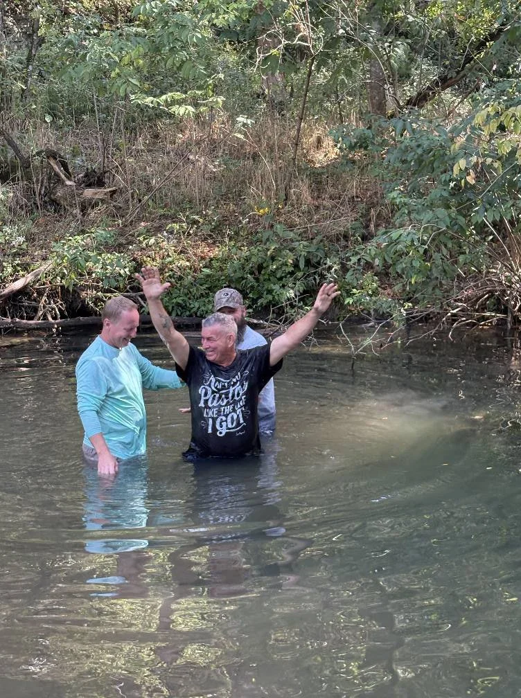 A man getting baptized in a creek at 12:2 Fellowship in Mountain View, AR.