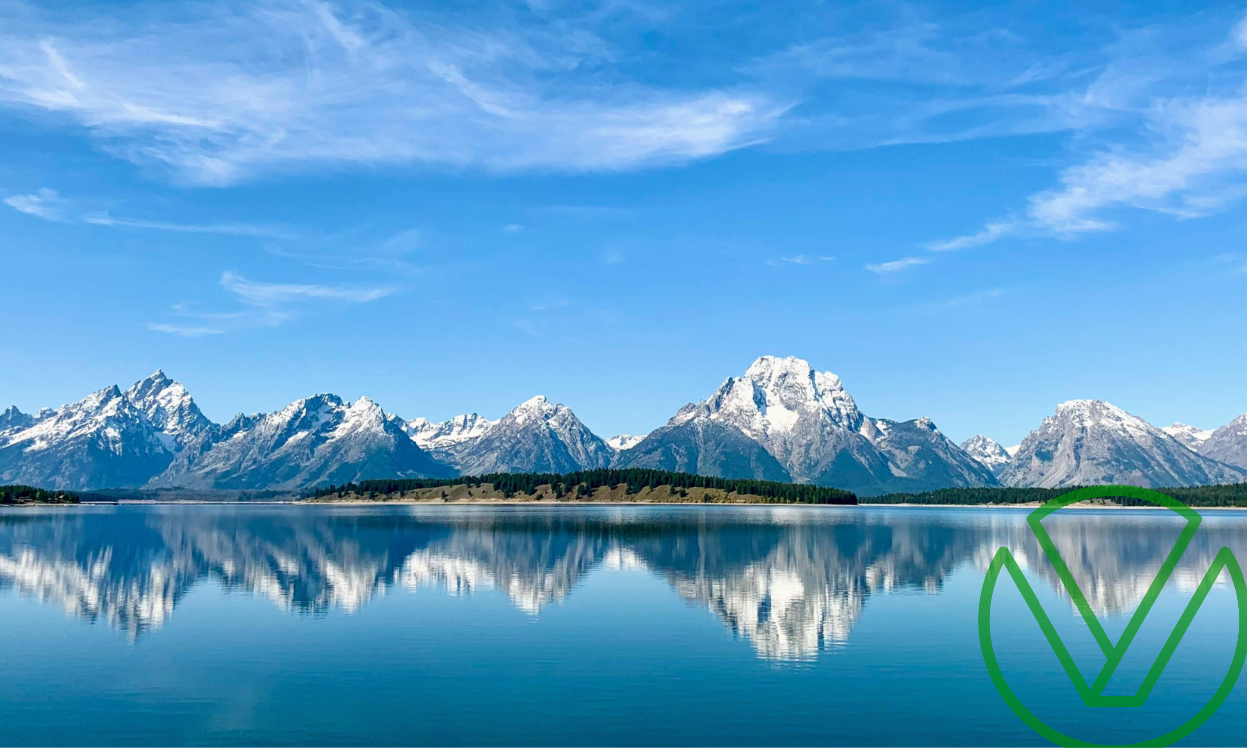 Scenic view of snow-capped mountains reflecting in a calm lake under a clear blue sky, symbolizing financial clarity and stability.