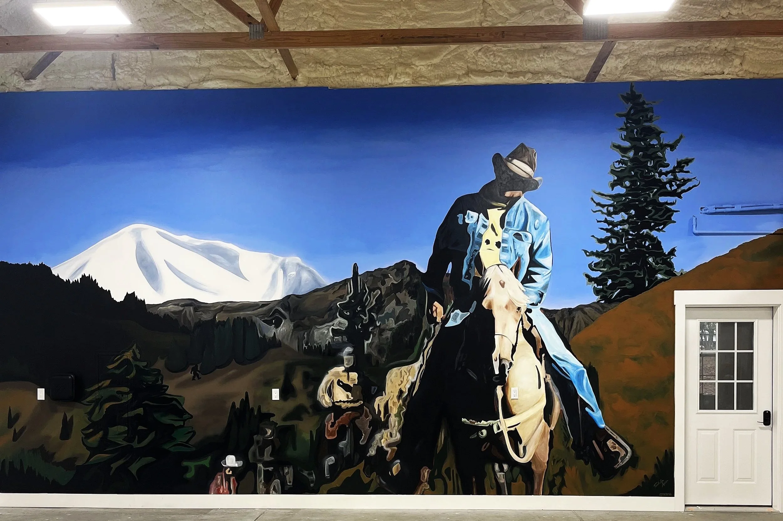 Wall mural depicting a cowboy riding a horse in a mountainous landscape with snow-capped peaks, evergreen trees, a person in a hat with a dog, and a white door on the right side.