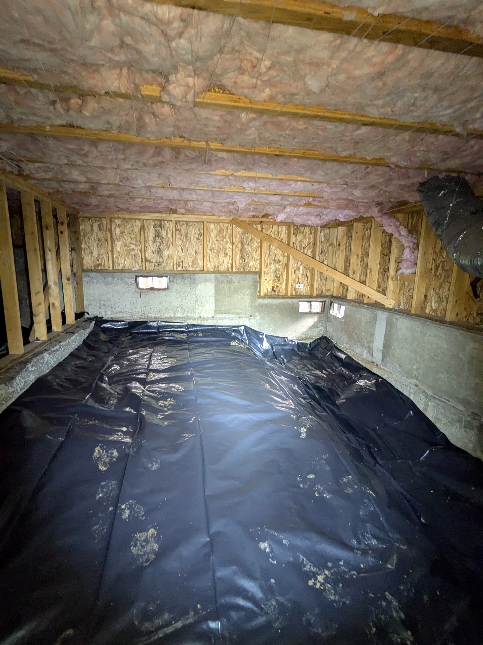 Insulation and vapor barrier in an attic or crawl space under construction.