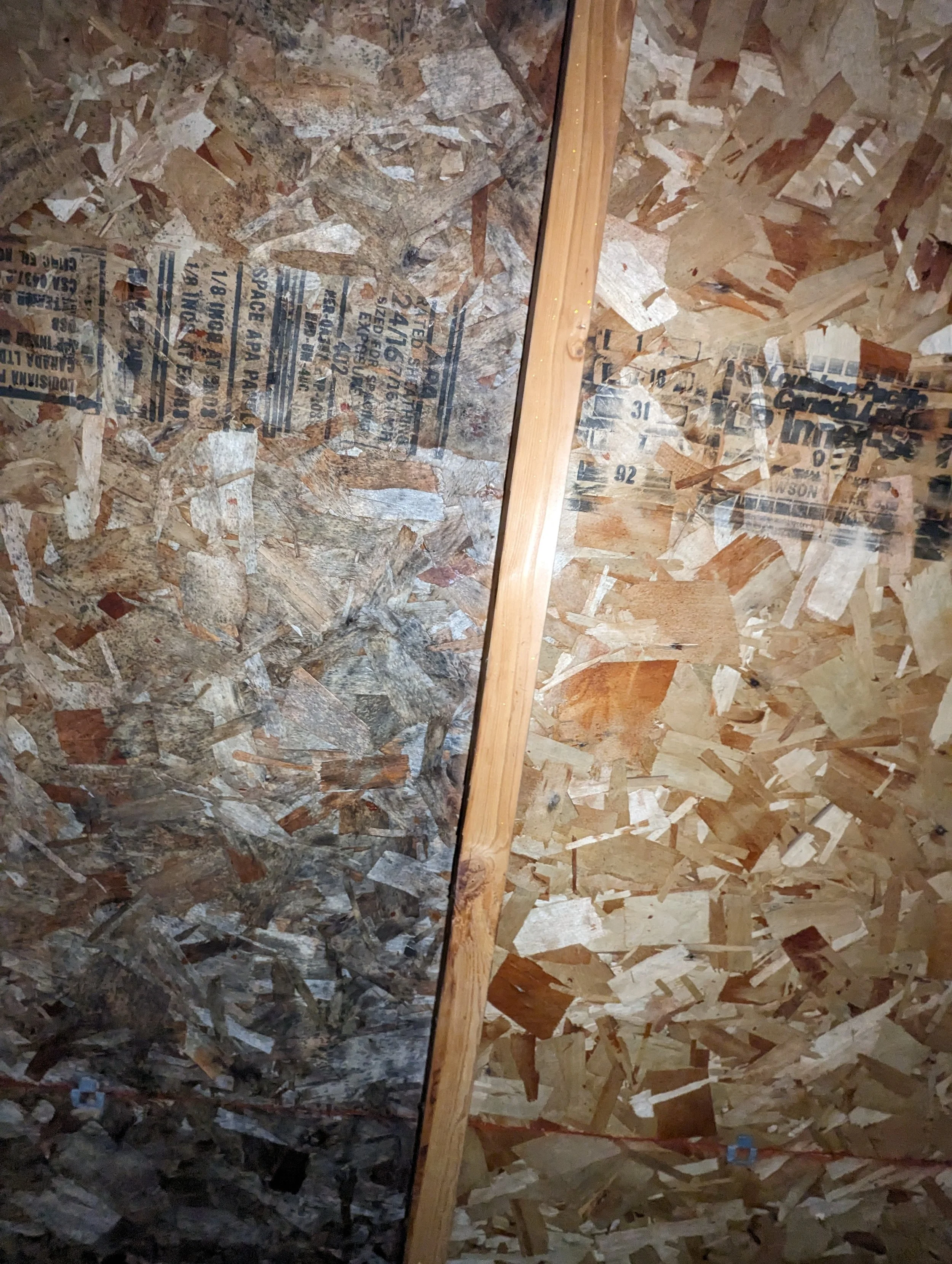 Interior of a wall made with OSB plywood panels and a wooden stud in the middle.