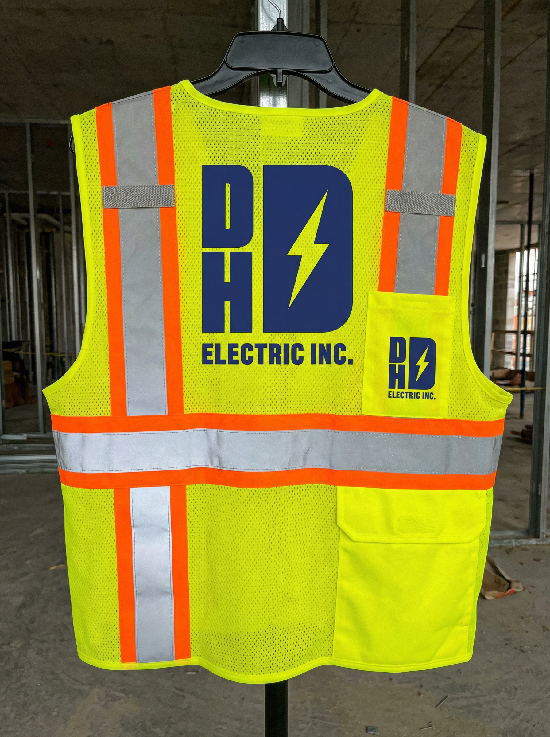 High visibility safety vest with the logo and branding of DHD Electric Inc., featuring a yellow background, reflective stripes, and a pocket with the company logo.