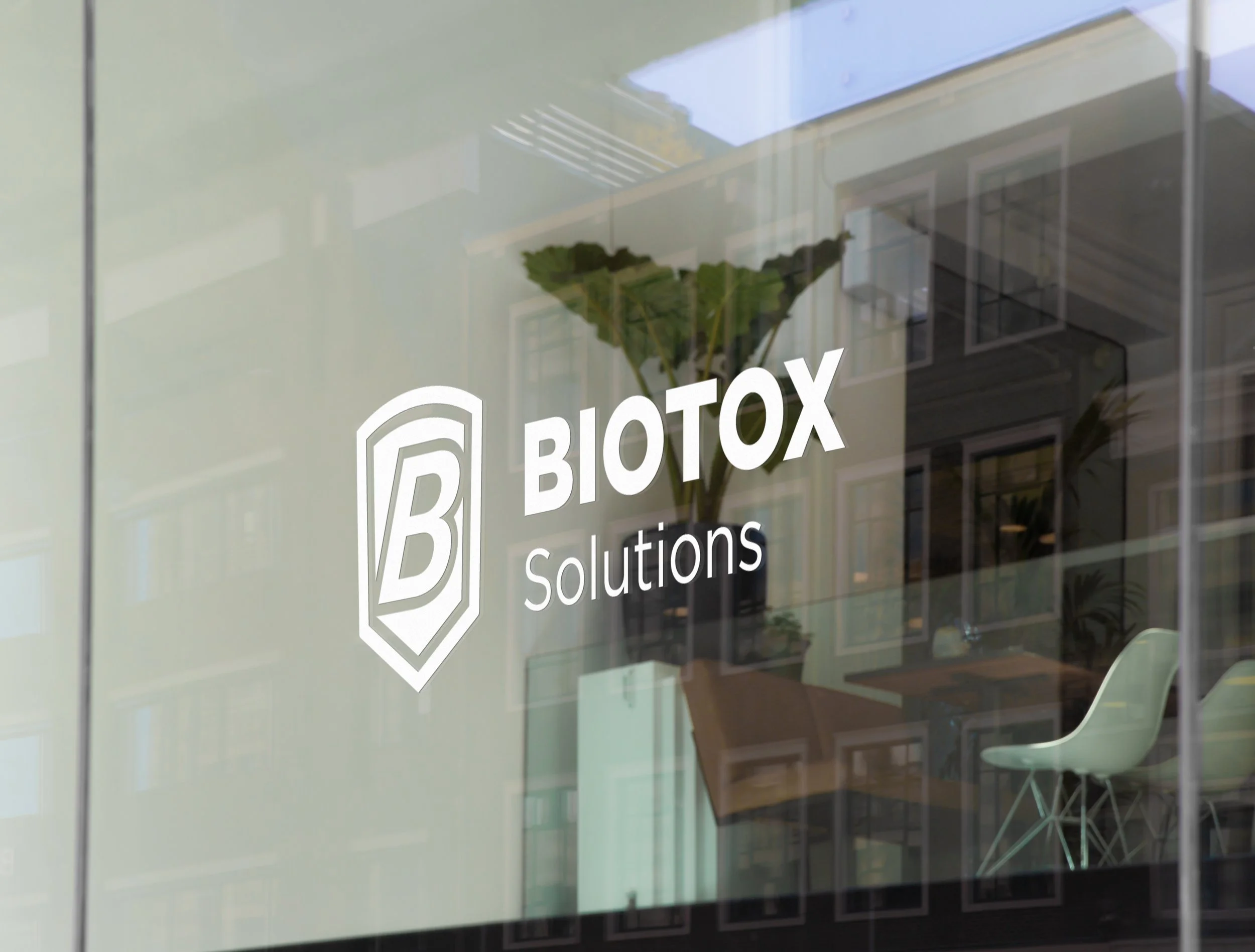Glass window with the logo and name of Biotox Solutions, with office interior reflections visible
