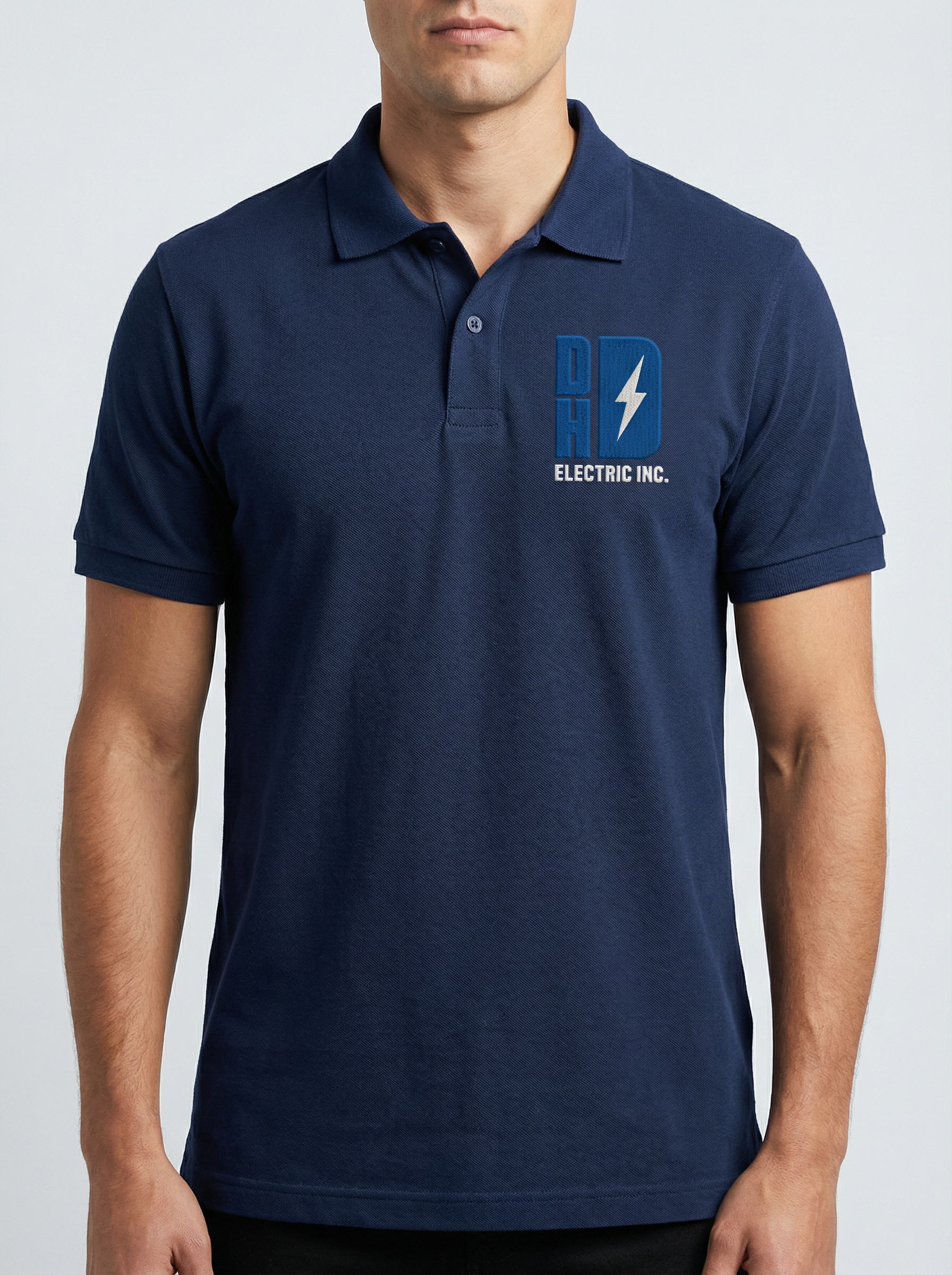 A man wearing a navy blue polo shirt with a logo on the chest that reads 'DHD Electric Inc.' with a lightning bolt symbol.