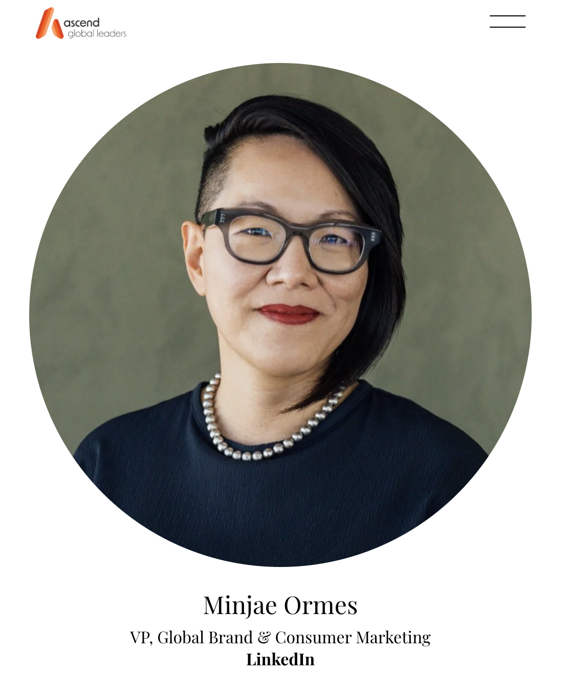 Professional portrait of Minjae Ormes, VP of Global Brand & Consumer Marketing, with glasses, short black hair, wearing a pearl necklace and a black top, smiling against a plain background.