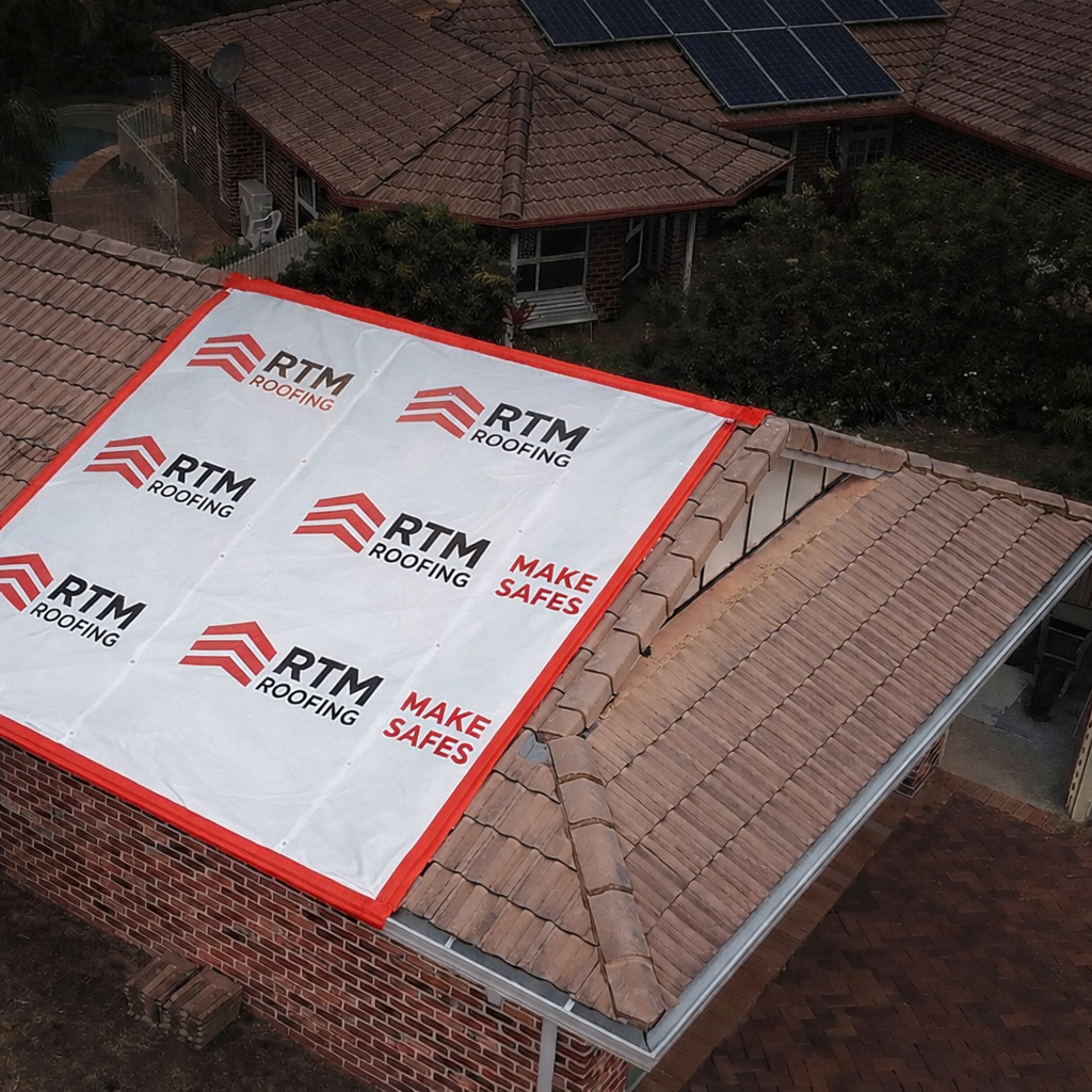 A rooftop under construction with roofing underlayment from RTM Roofing, with cranes and neighboring houses visible.