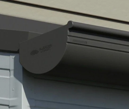 Close-up of a grey gutter guard with the brand name 'Leaf Filter' attached to a house's gutter system.