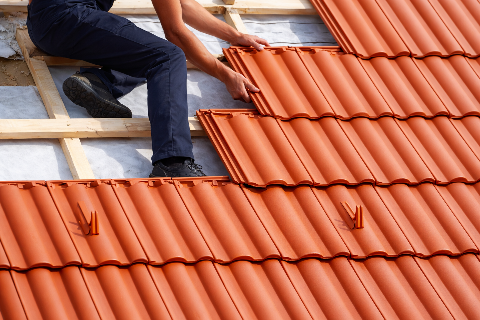 A person installing orange roof tiles on a sloped roof.