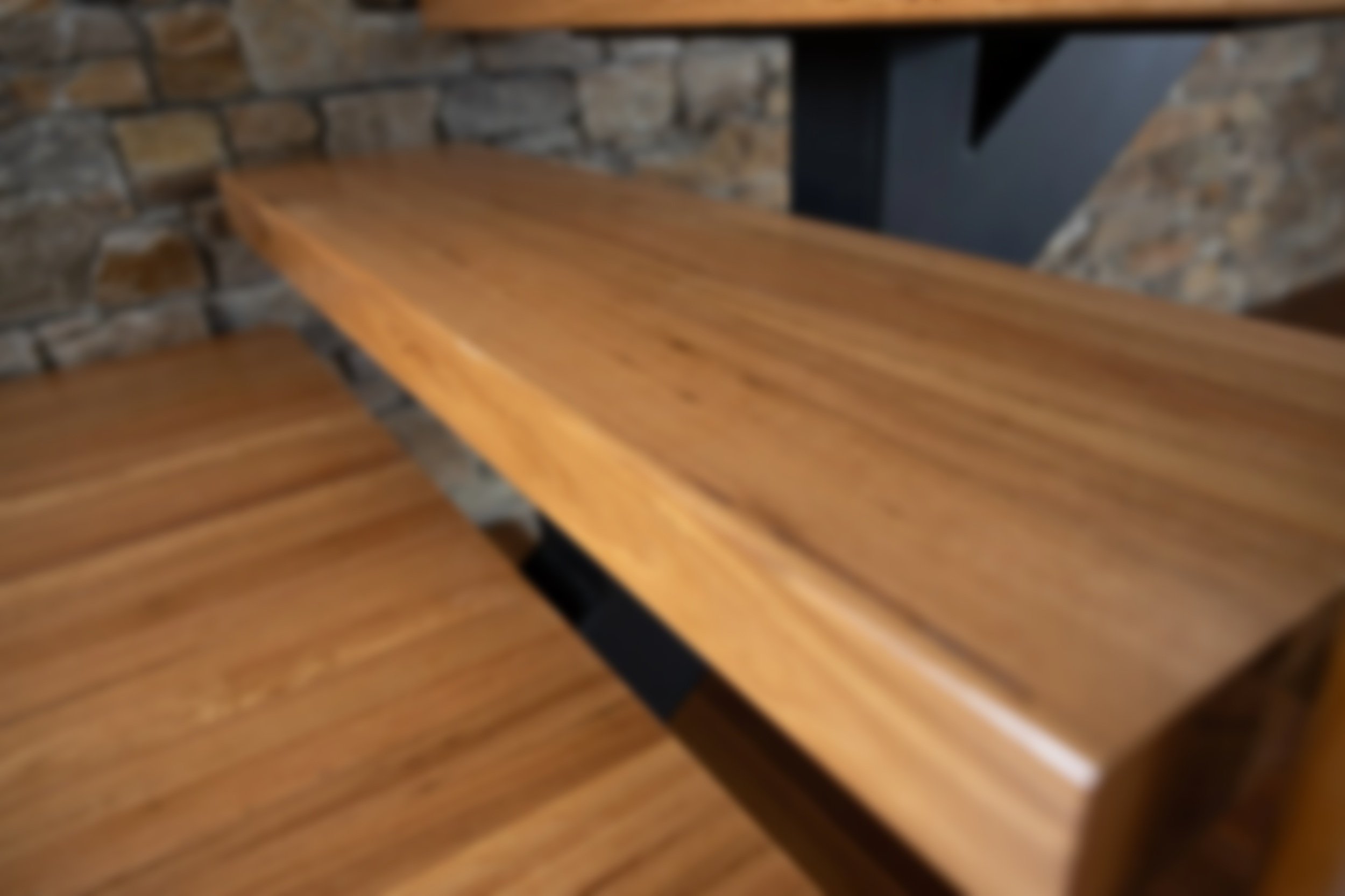 Close-up of a luxury wooden staircase against a stone wall in a modern home.