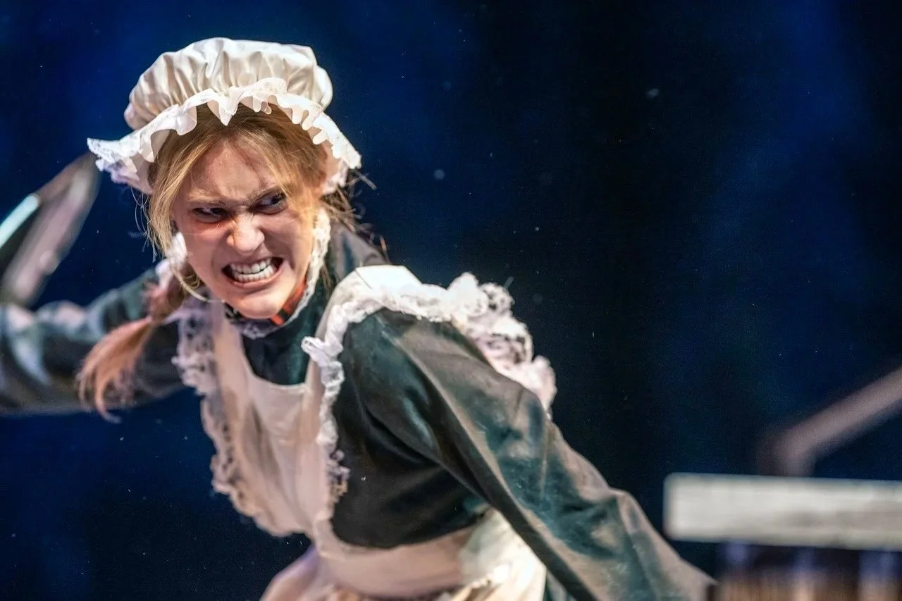 Faith Hargadon as Boggett in Pheobe in Winter by Jen Silverman. A person dressed as a maid with a white apron and cap, angrily swinging a frying pan.