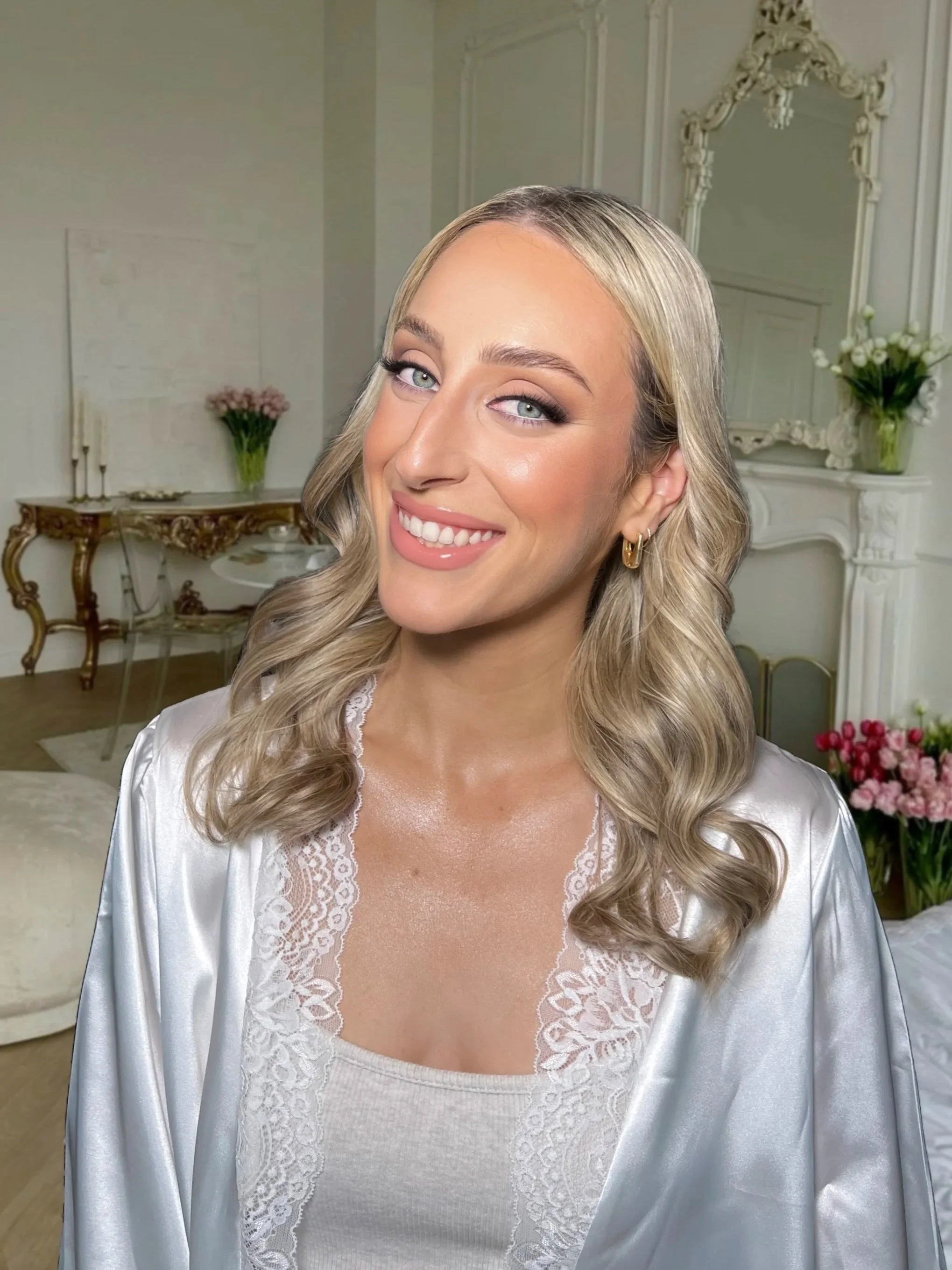 Bride with soft glam makeup and loose waves smiling in an elegant getting-ready suite, Melbourne bridal makeup by Anastasia.