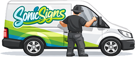 A person wearing a black hat and black shirt puts up a vibrant Sonic Signs vinyl wrap on a white delivery van, featuring blue, green, and yellow graphics.