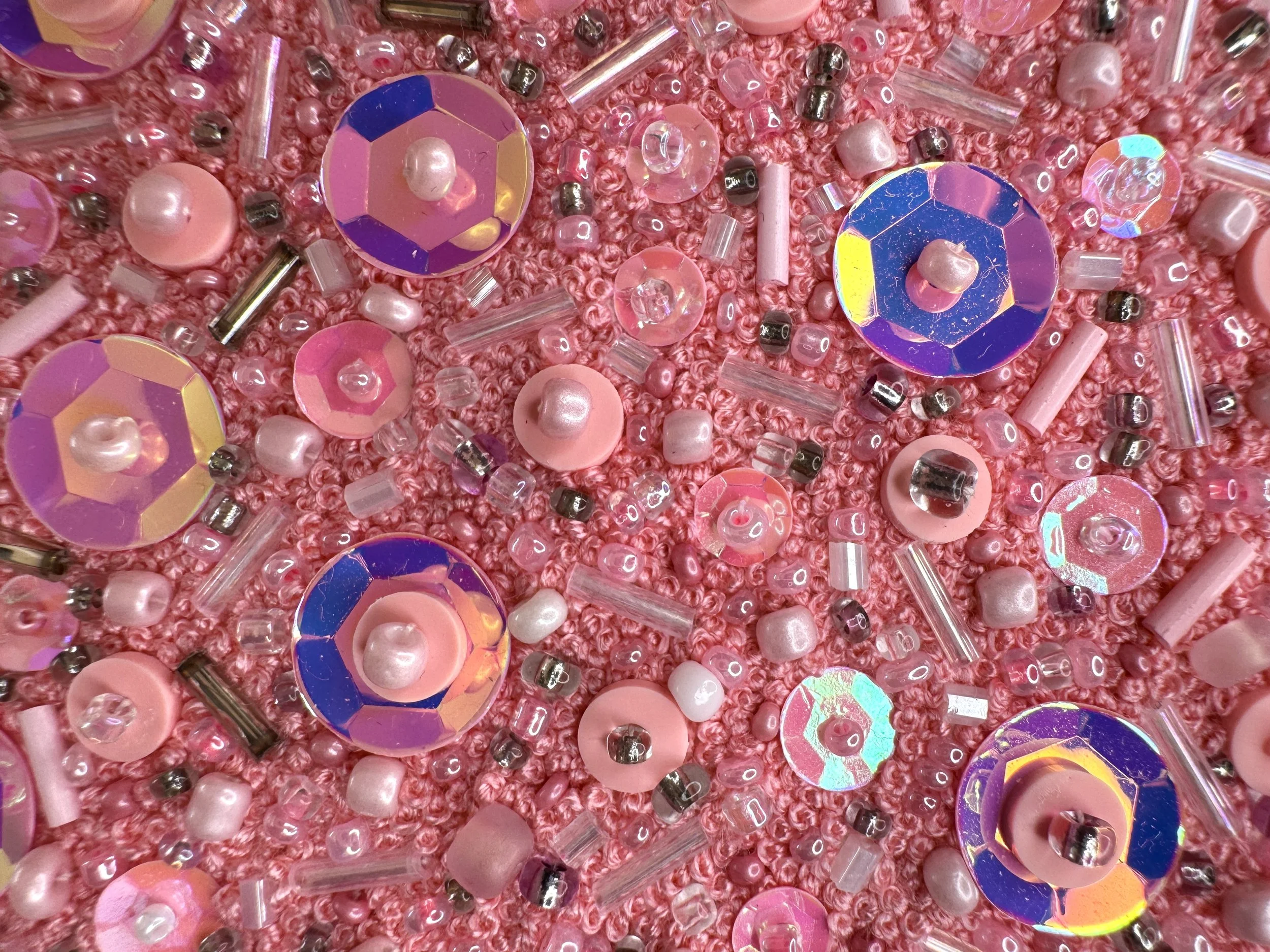 Close-up of pink beads and holographic sequins in a bed of hand embroidered French knots.